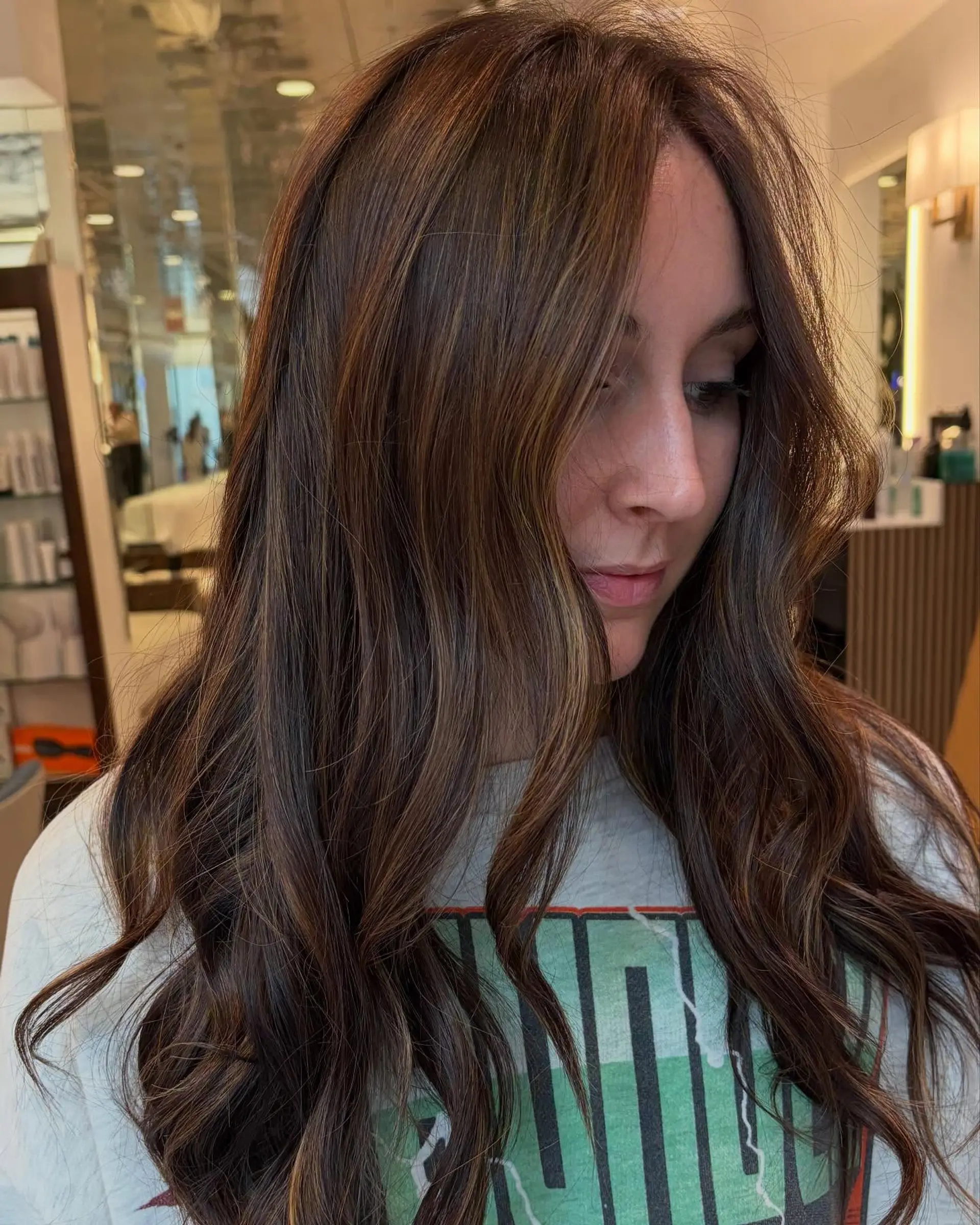 Long wavy brunette hair enhanced with subtle honey-toned balayage highlights. 1