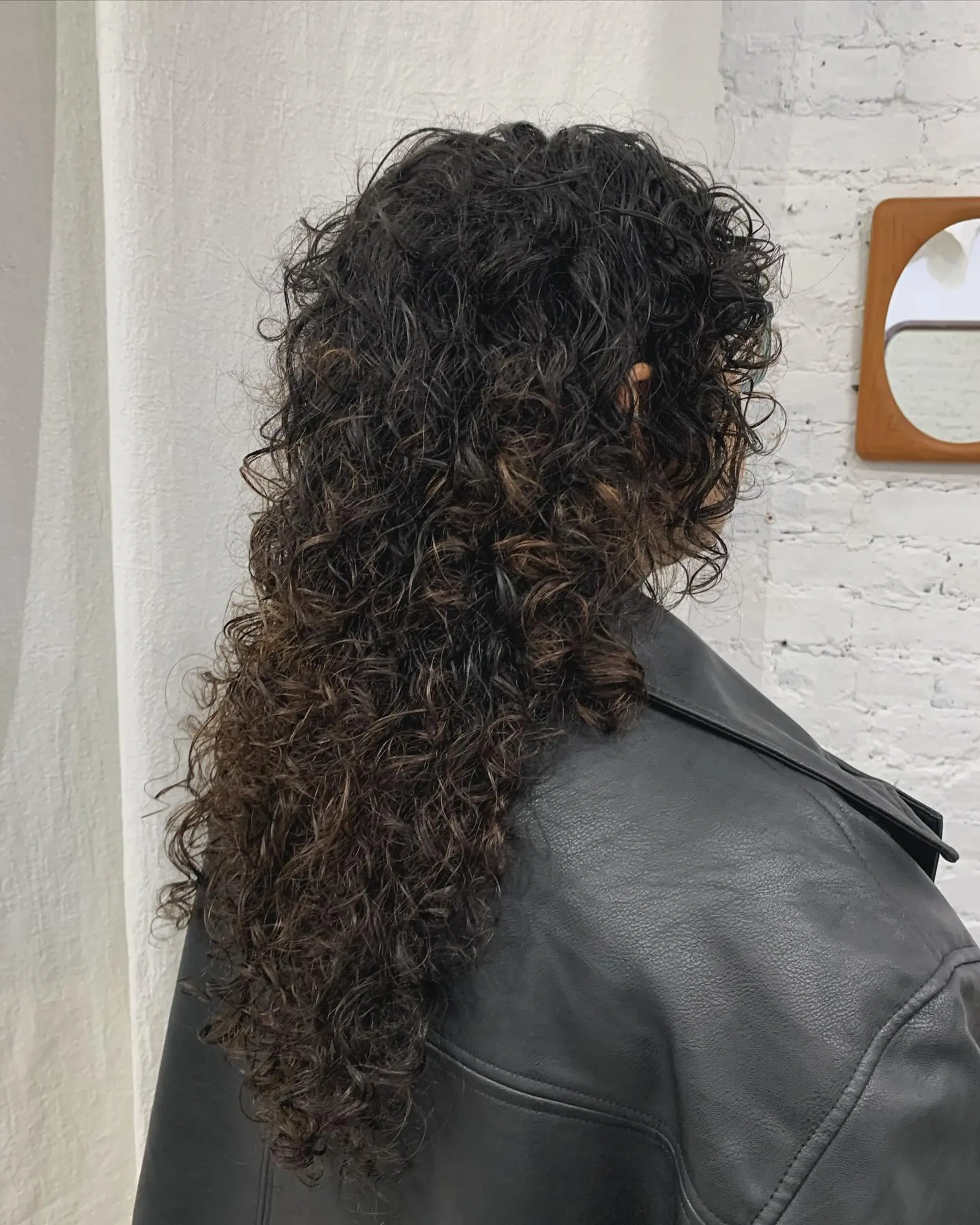 Long, dark brown curly hair with a full fringe and cascading voluminous ringlets. 2