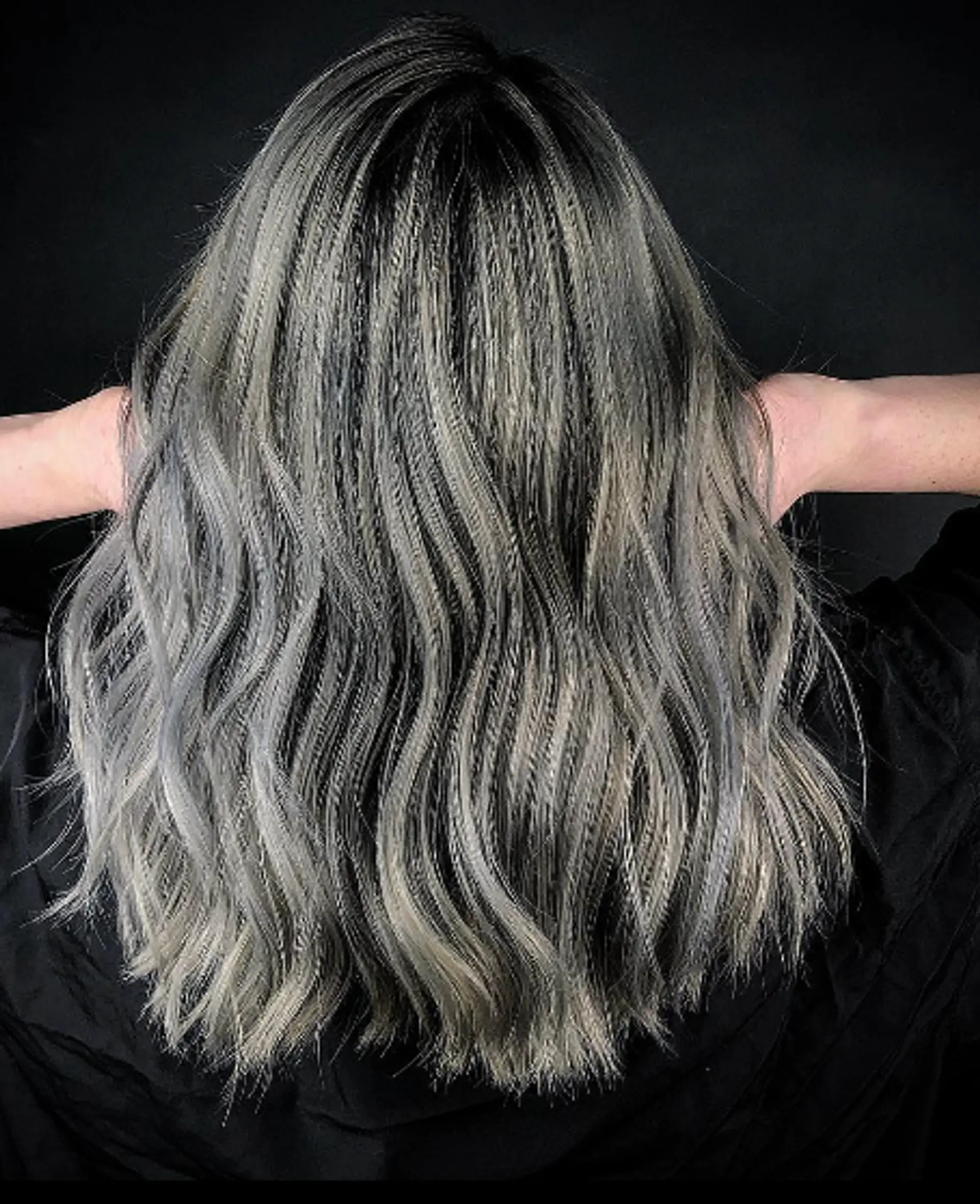 Long, wavy hair with an ombre transition from dark black roots to silver and gray tones, featuring sleek and voluminous waves. 1
