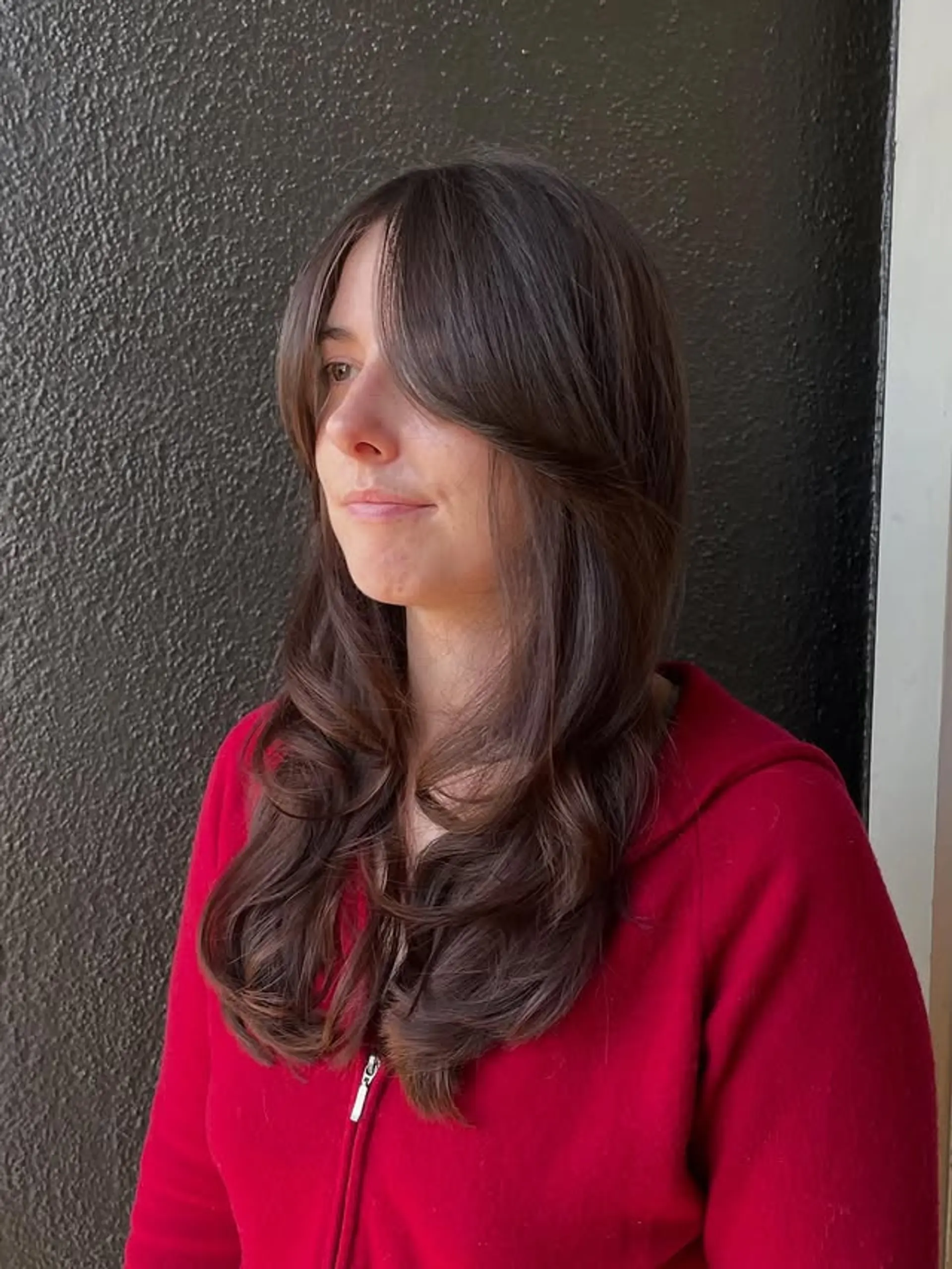 Long wavy hair with curtain bangs and layered cut. 1