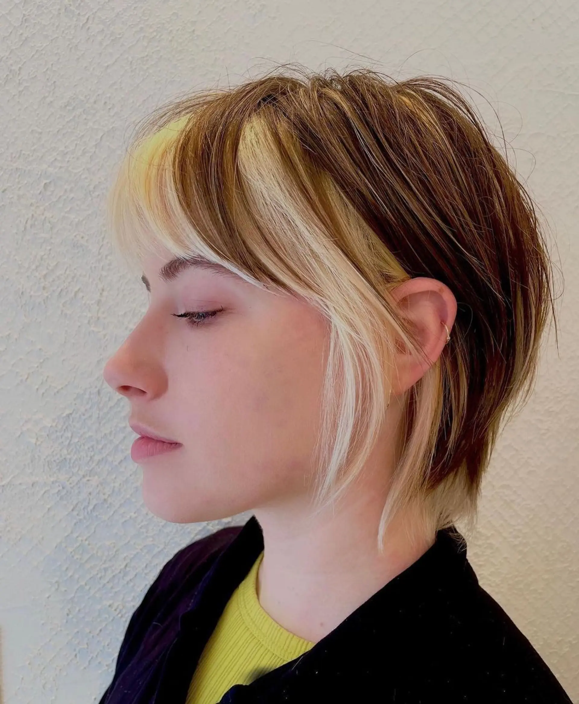 Chic, edgy layered pixie with blonde and brown tones, featuring contrasting highlights, a face-framing fringe, and a tapered back. 1
