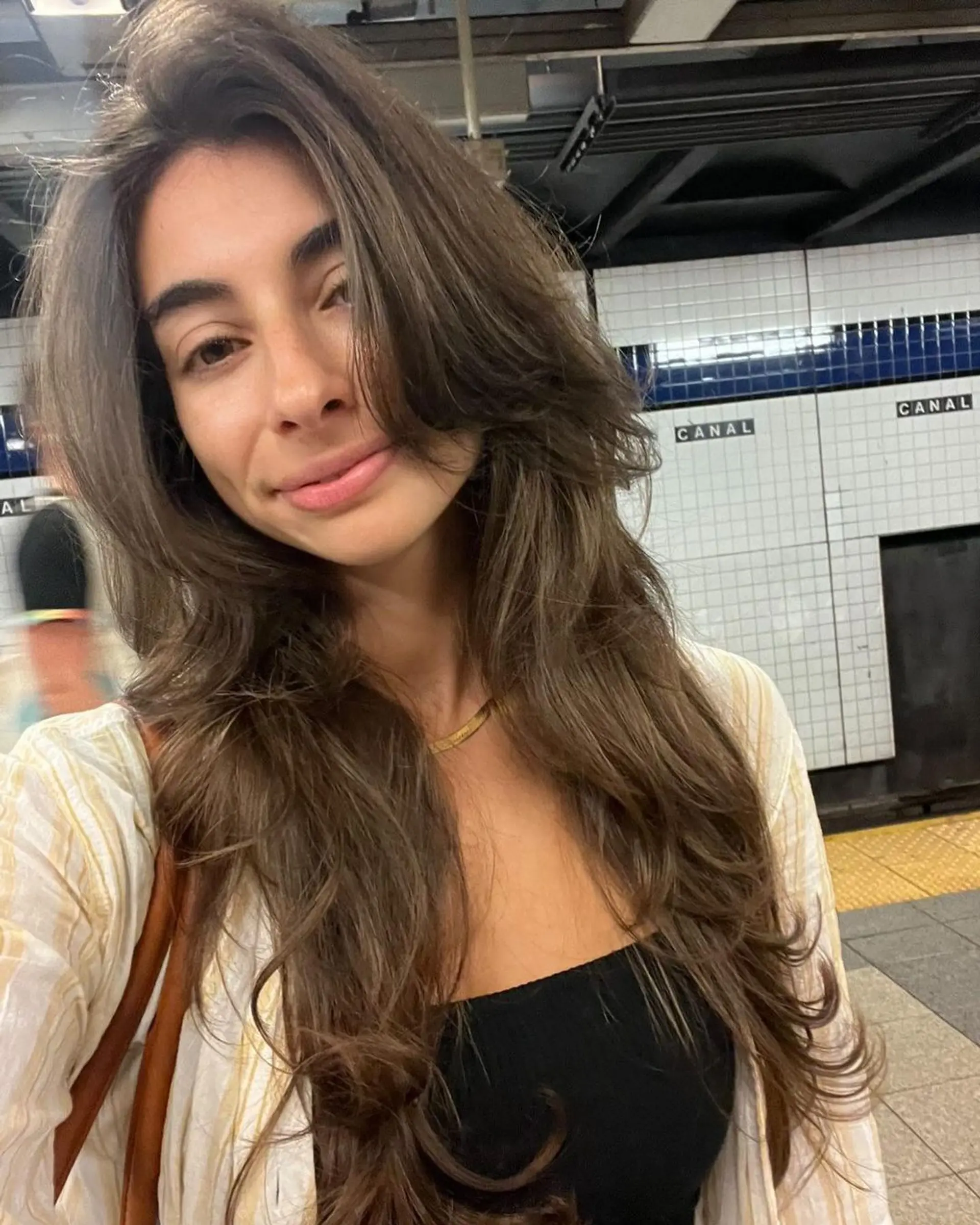 Long, wavy chestnut brown hairstyle with side-swept bangs, face-framing layers, and voluminous waves for a natural look. 1