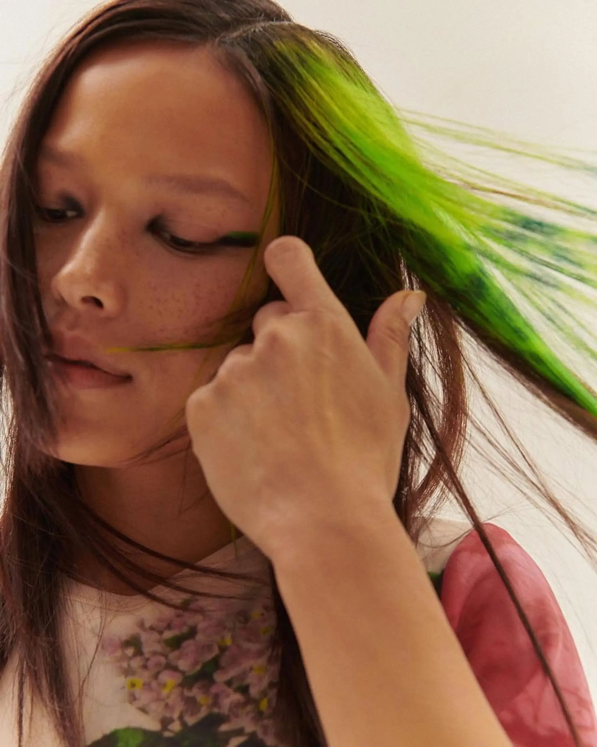 Long, straight hair with an asymmetrical vibrant green streak, creating a dynamic visual effect.