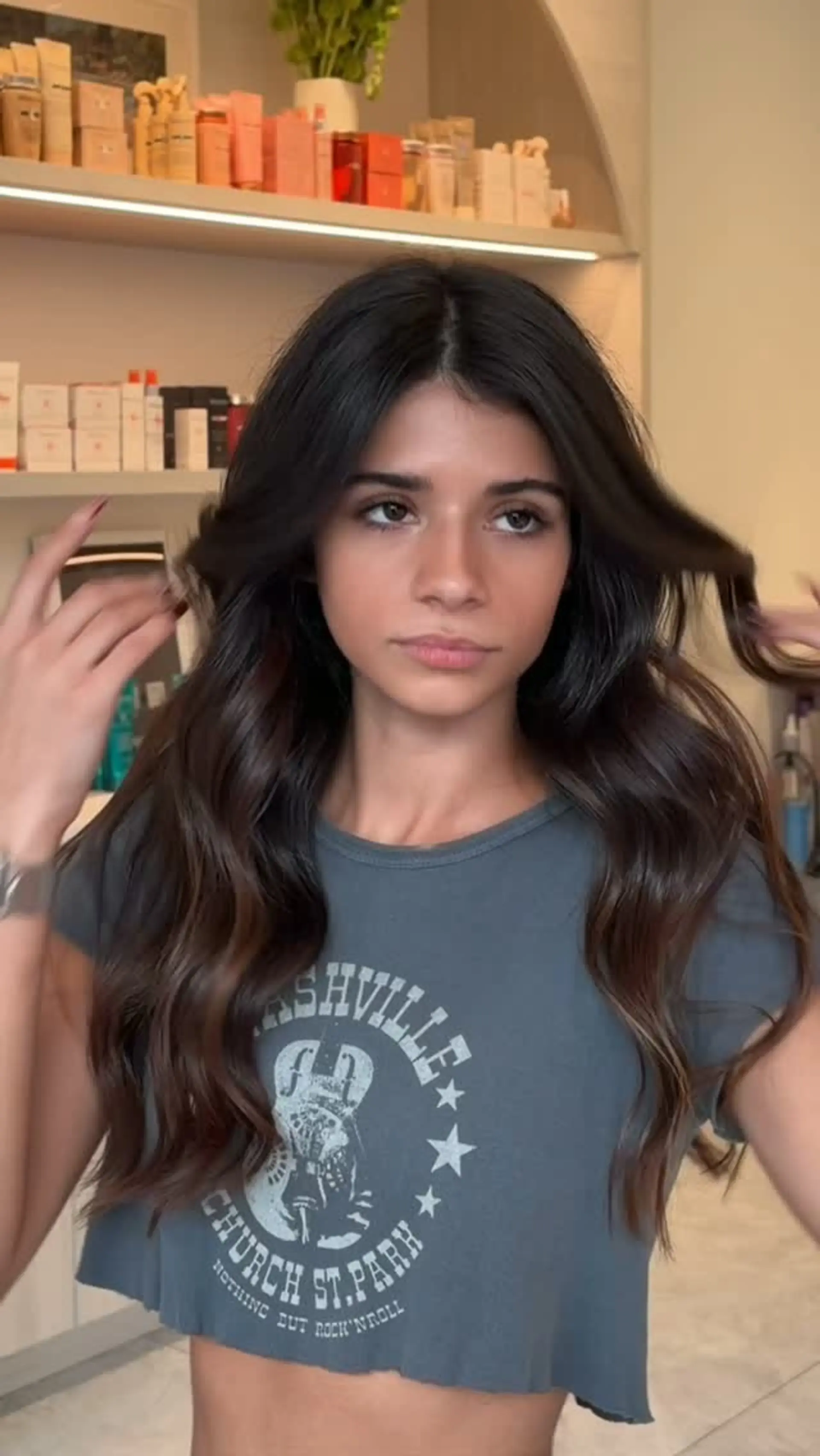 Long, glossy chocolate brown hair styled with voluminous loose waves and a center part. Estimate scope: Toner/gloss component only, from $50. The pictured blowout/waves, haircut or other color work are not priced by this mapping. No claim of a complete finished-look quote. 1