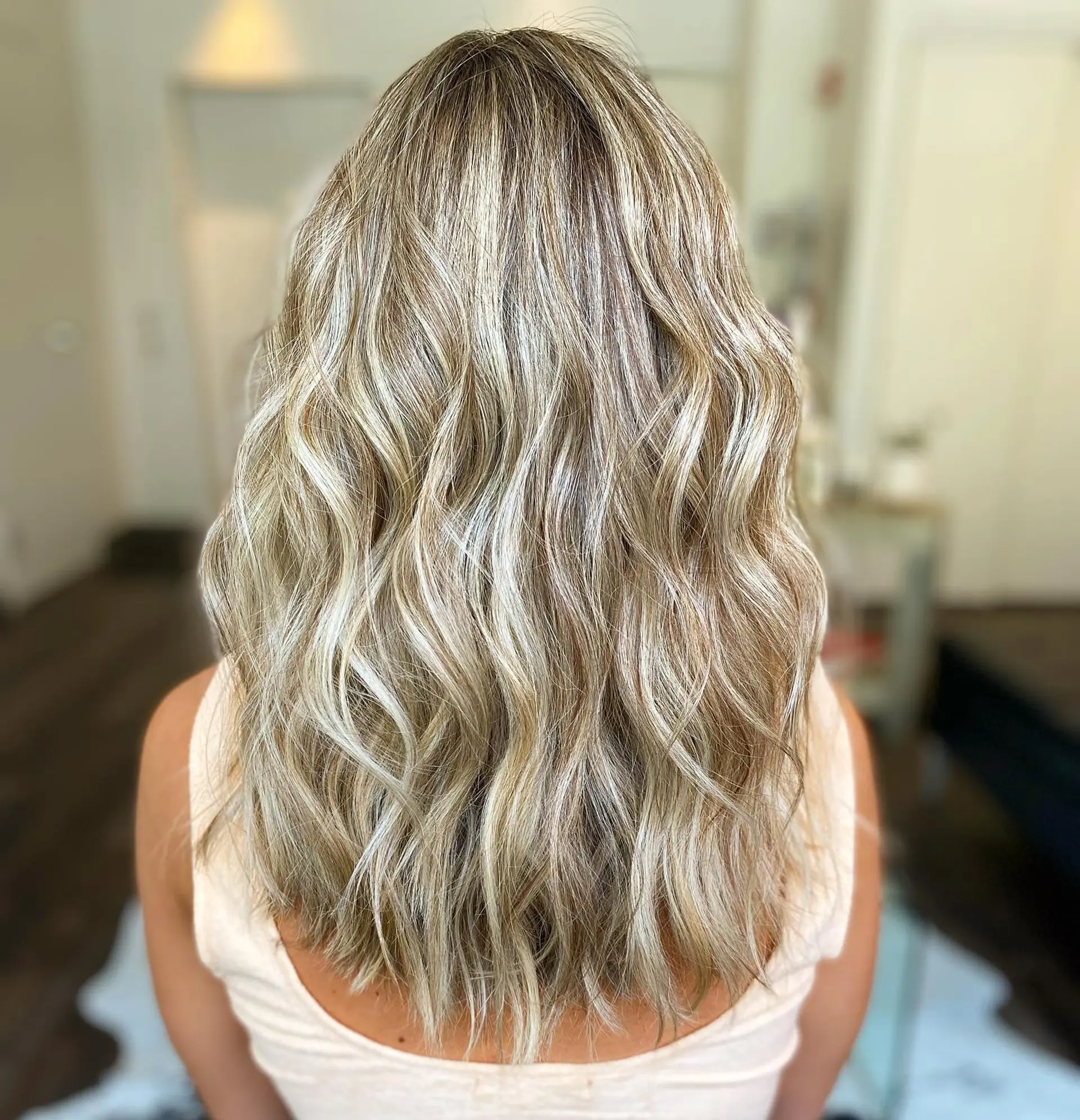 Long cool-toned blonde hair featuring dimensional highlights and a blended root, styled in soft, loose waves. 1