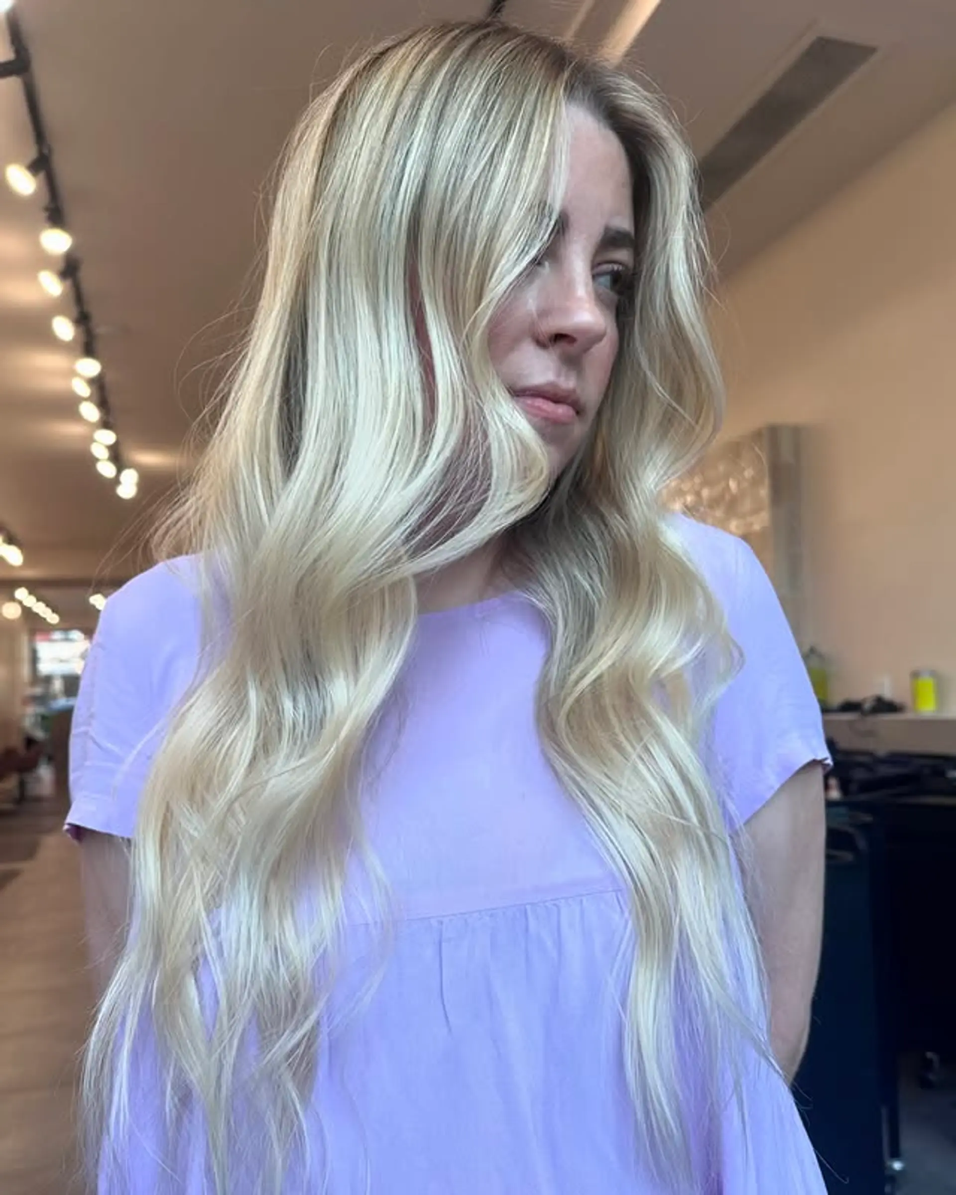 Long, wavy hairstyle with an icy blonde color and a shadow root. Features face-framing layers. 1