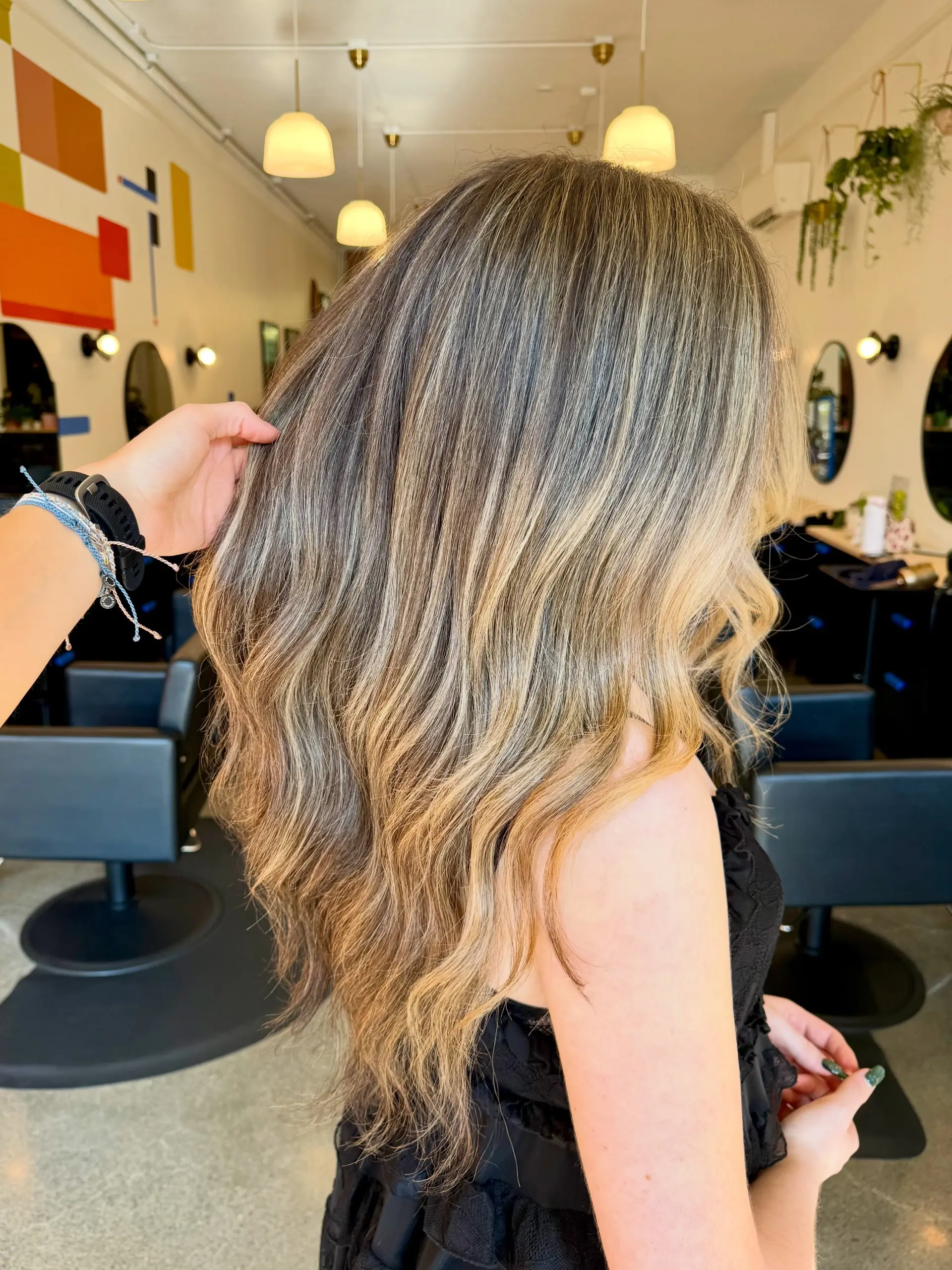 Long wavy hair featuring seamless golden blonde foil highlights blended over a natural light brown base. 1