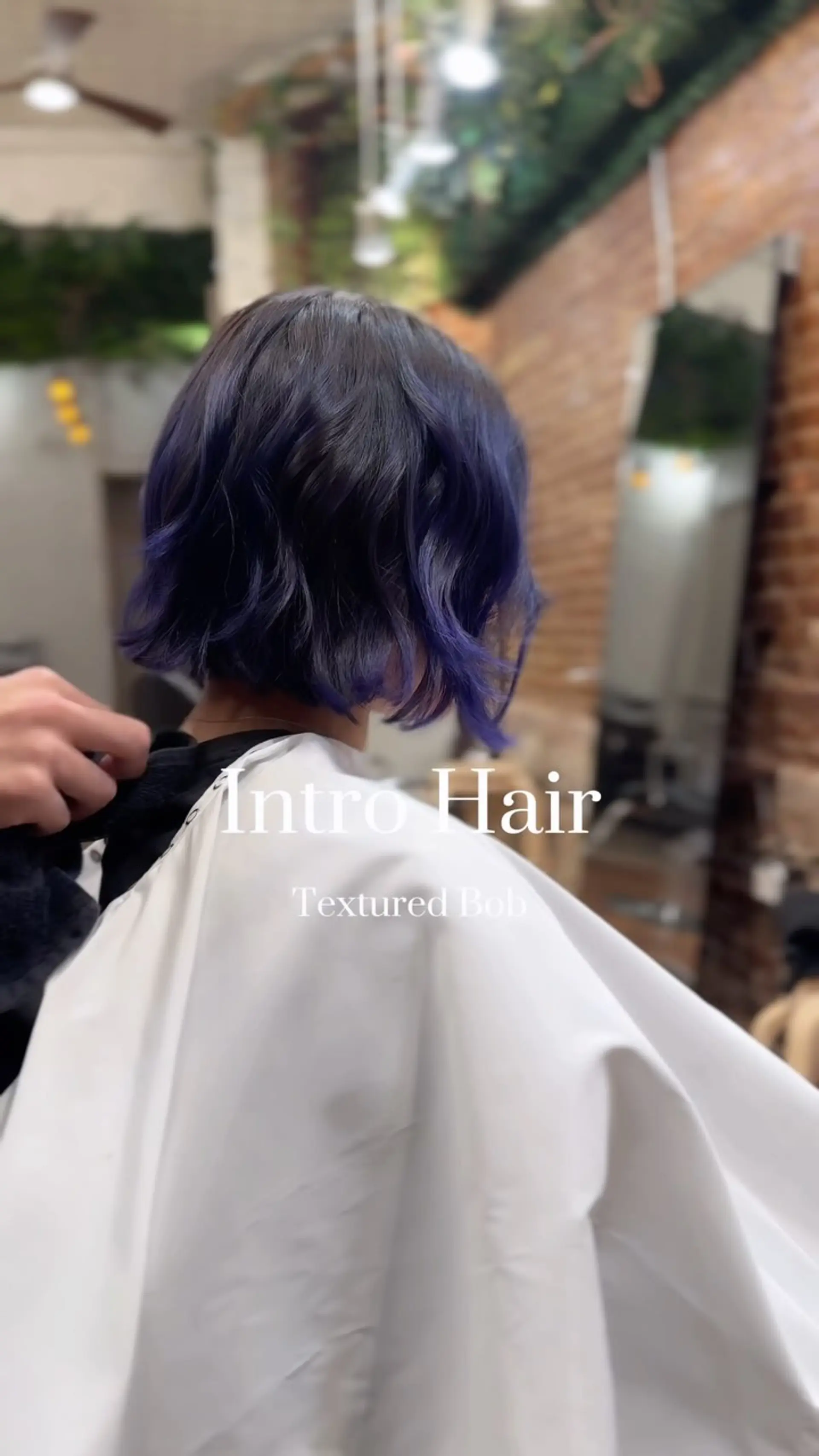 A chin-length textured bob cut featuring subtle waves and deep indigo-purple tones over a dark base. 1