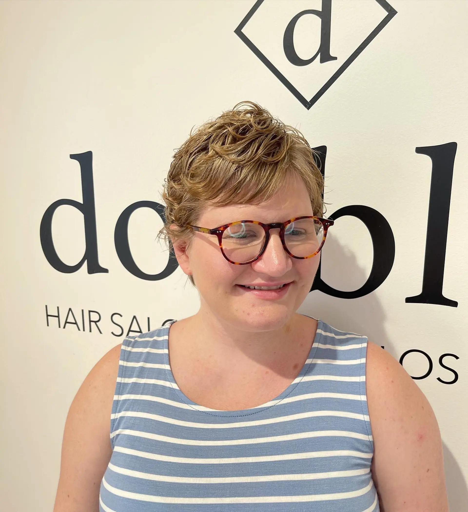 A cropped pixie haircut featuring light body waves and subtle curls styled with soft bangs sweeping across the forehead. 1