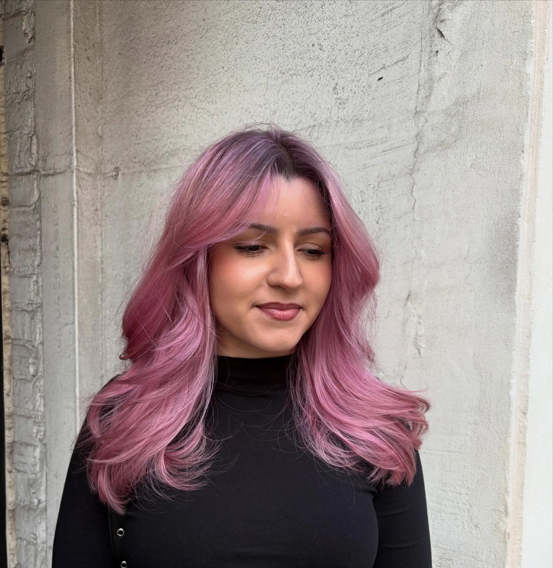 Medium-length pastel pink hair styled with layered curtain bangs and soft, flipped blowout ends. 1