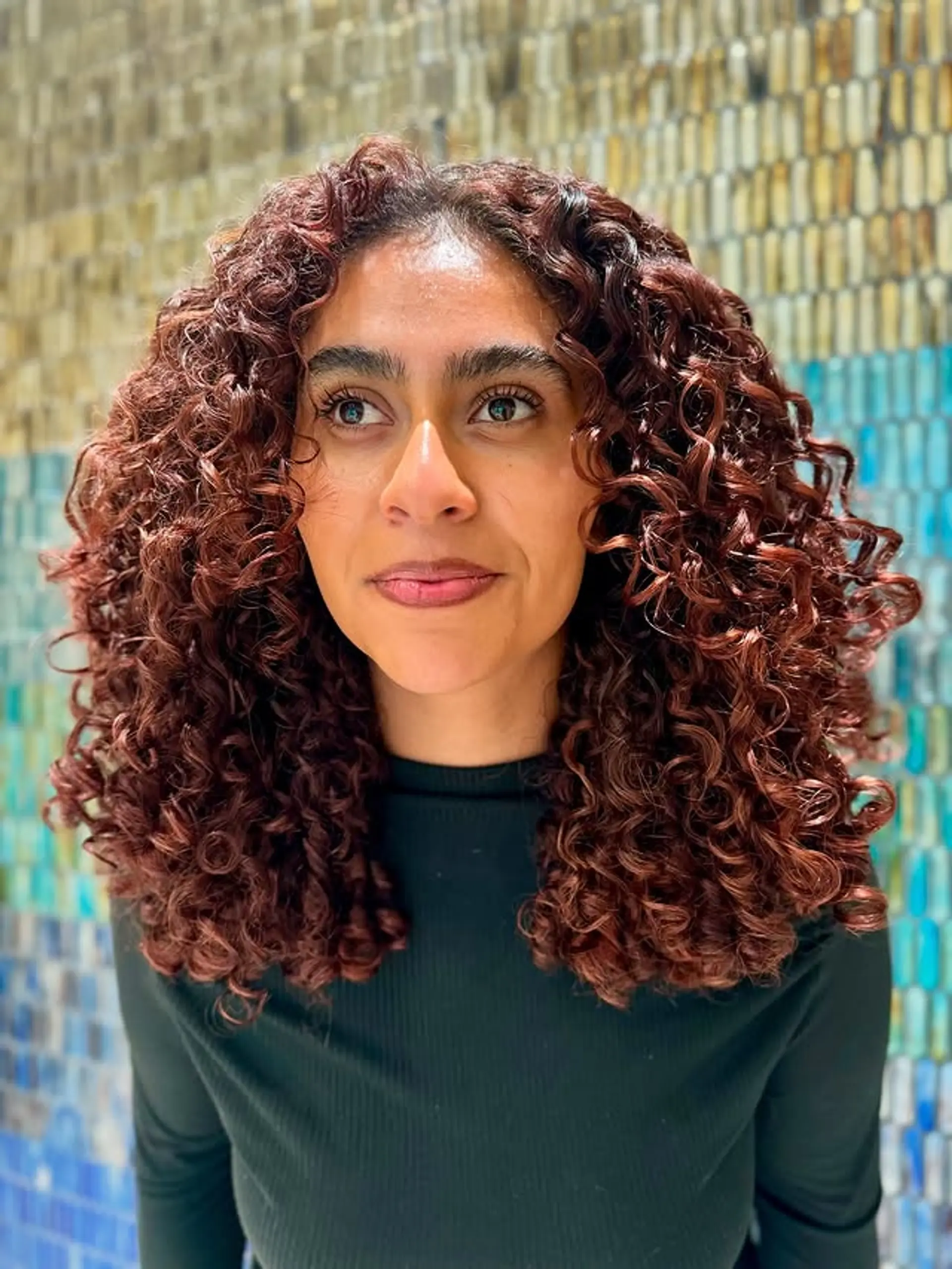 A stylish medium-length cut that accentuates defined curls with a vibrant copper hue. 1