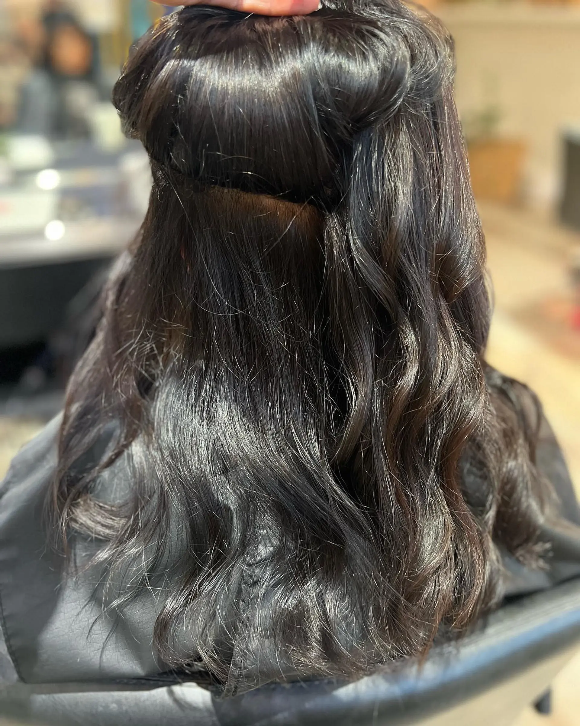 Medium-length dark brunette wavy hair showing an invisible row of extensions installed for natural fullness. 1