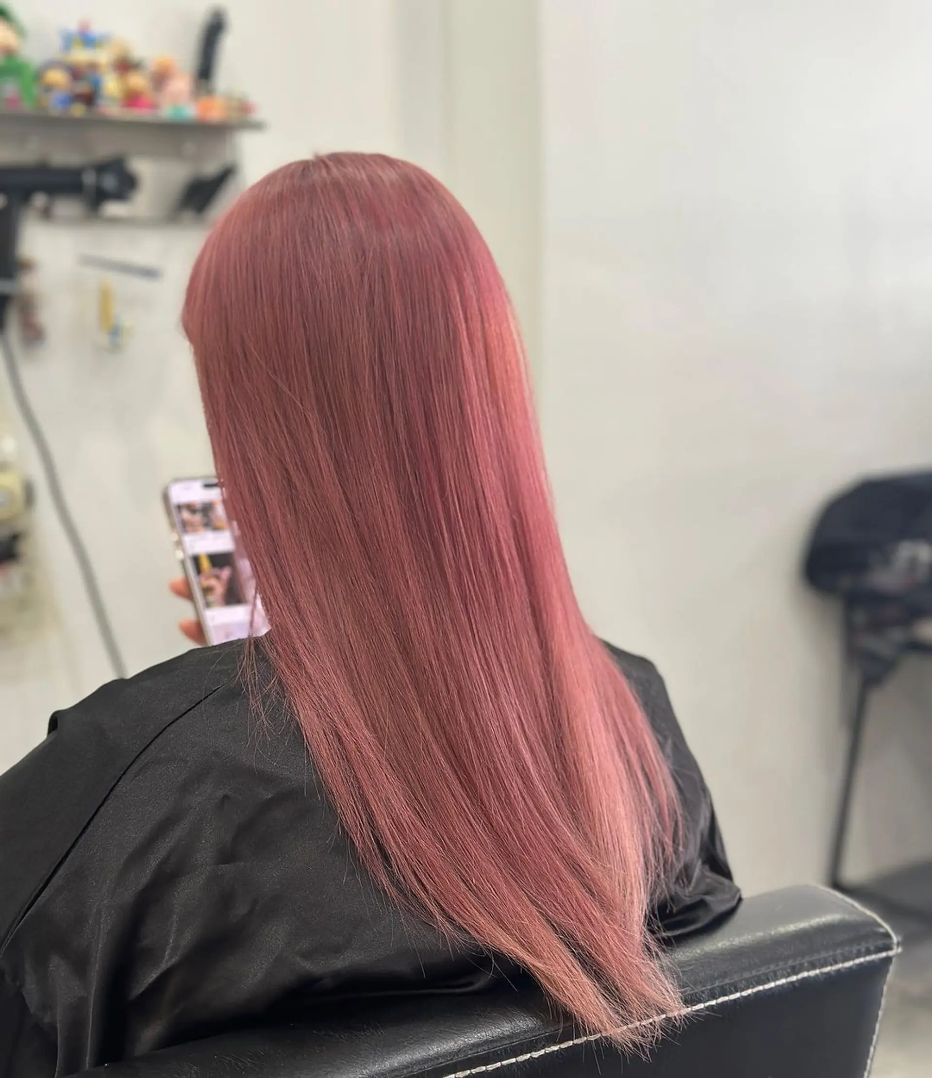 A stunning long and straight hairstyle with a sleek and smooth texture. The hair is colored in a vibrant blend of rose gold and pink, giving it a trendy and minimalist appearance with a rich, monochrome look. 1