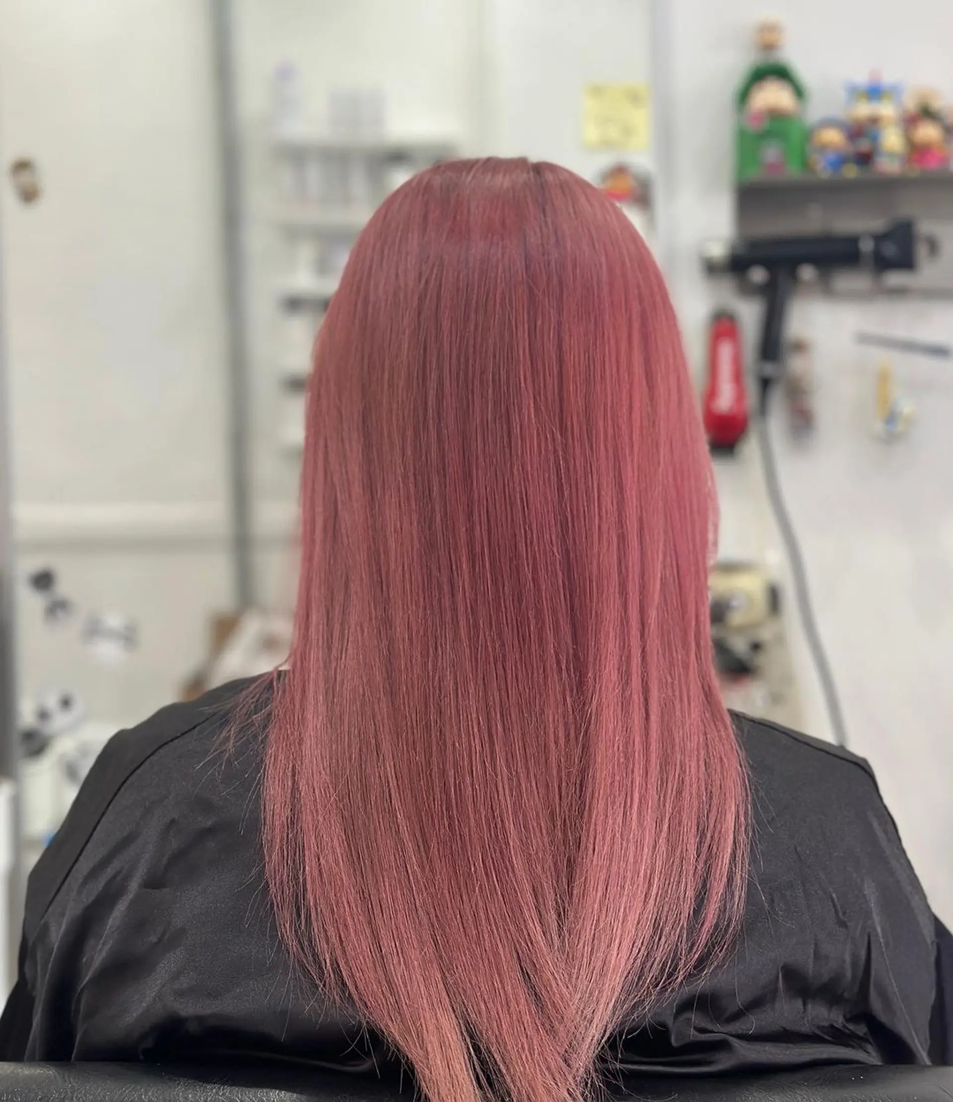 A stunning long and straight hairstyle with a sleek and smooth texture. The hair is colored in a vibrant blend of rose gold and pink, giving it a trendy and minimalist appearance with a rich, monochrome look. 2