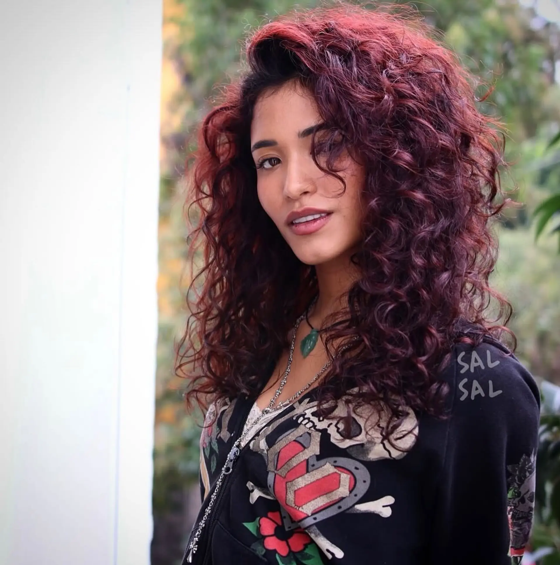 Medium-length voluminous curly style with defined ringlets in a rich burgundy shade, styled with a deep side sweep. 1