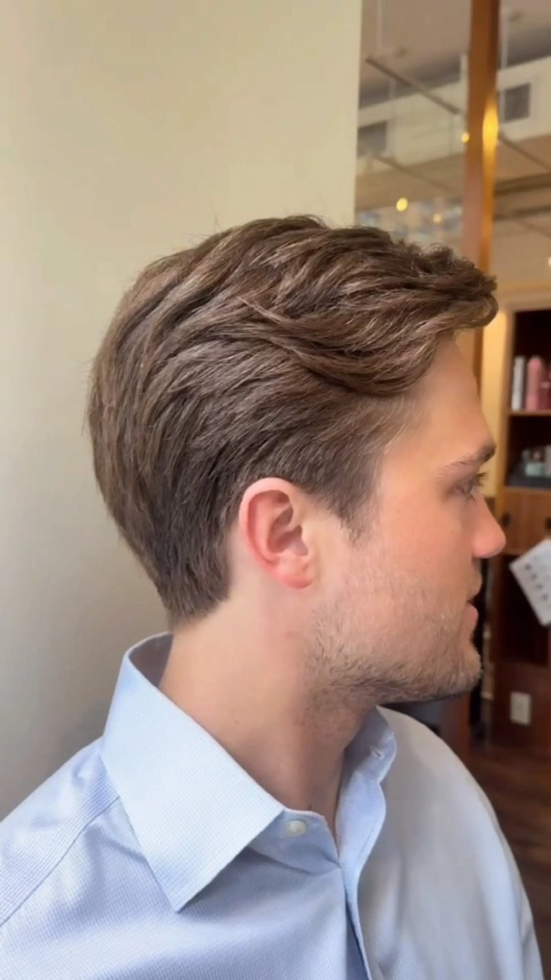 A clean, classic men's haircut featuring softly tapered sides and a natural wavy texture on top. 1