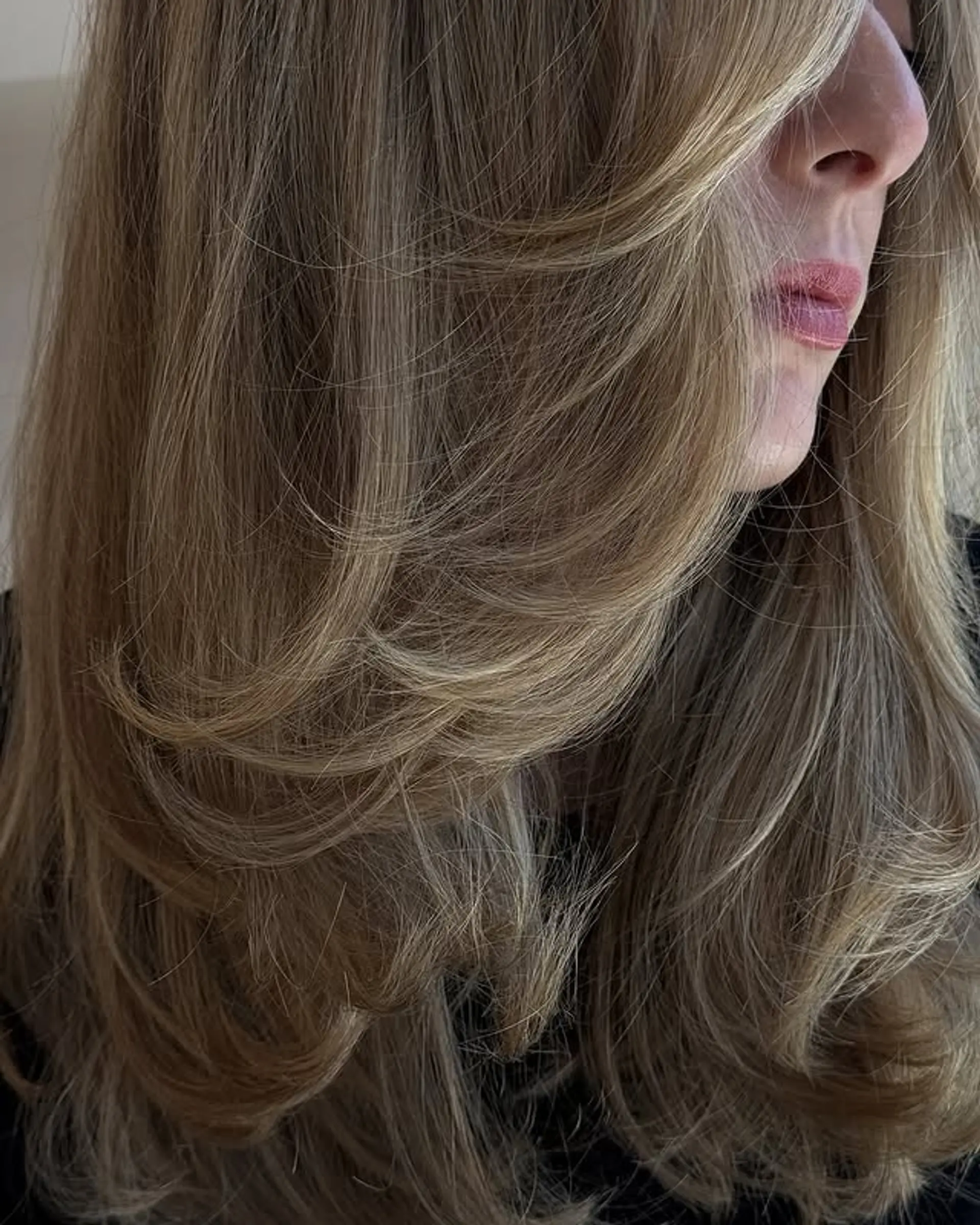 A medium-length, layered haircut with a subtle bronde balayage, featuring face-framing layers. 1