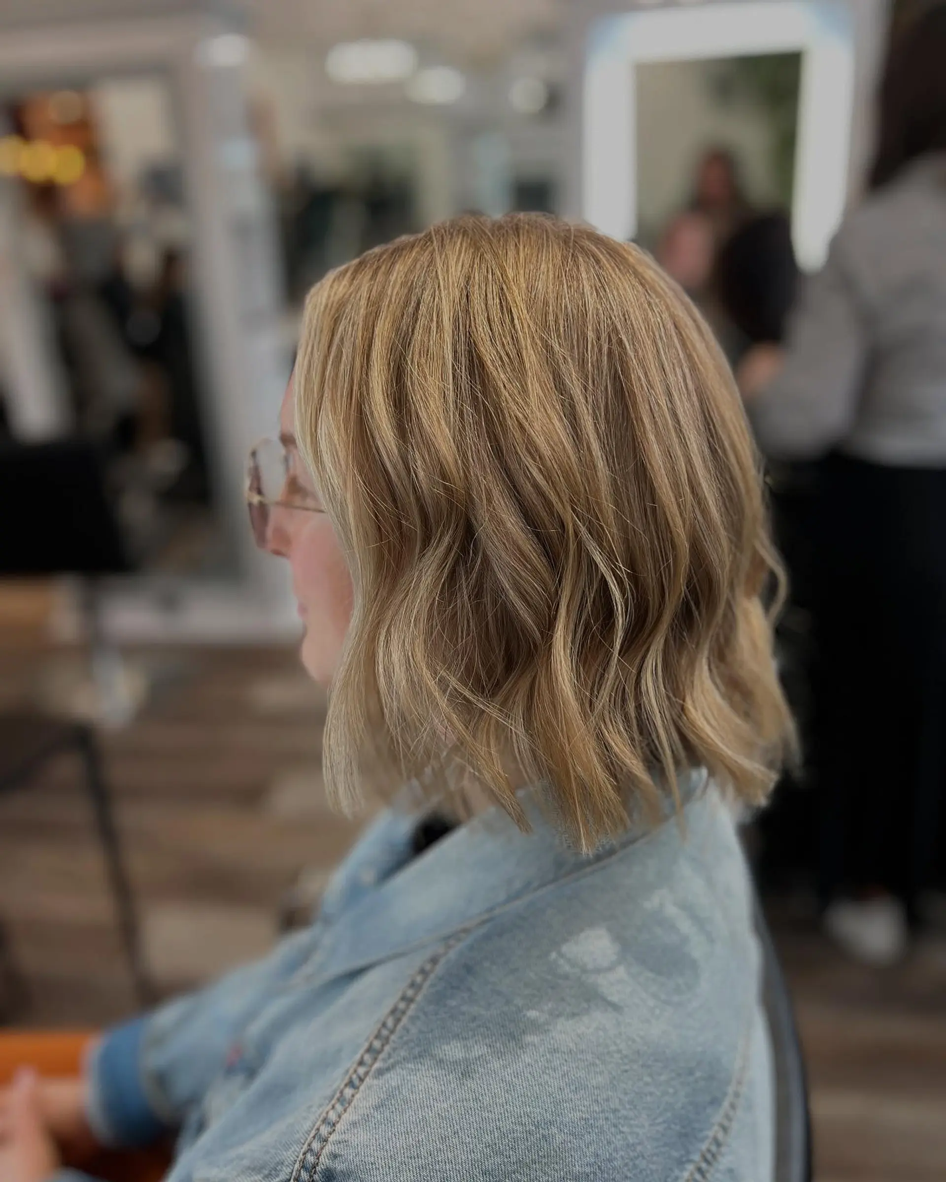 A textured, neck-length bob styled with soft lived-in waves and multi-dimensional blonde highlights. 1