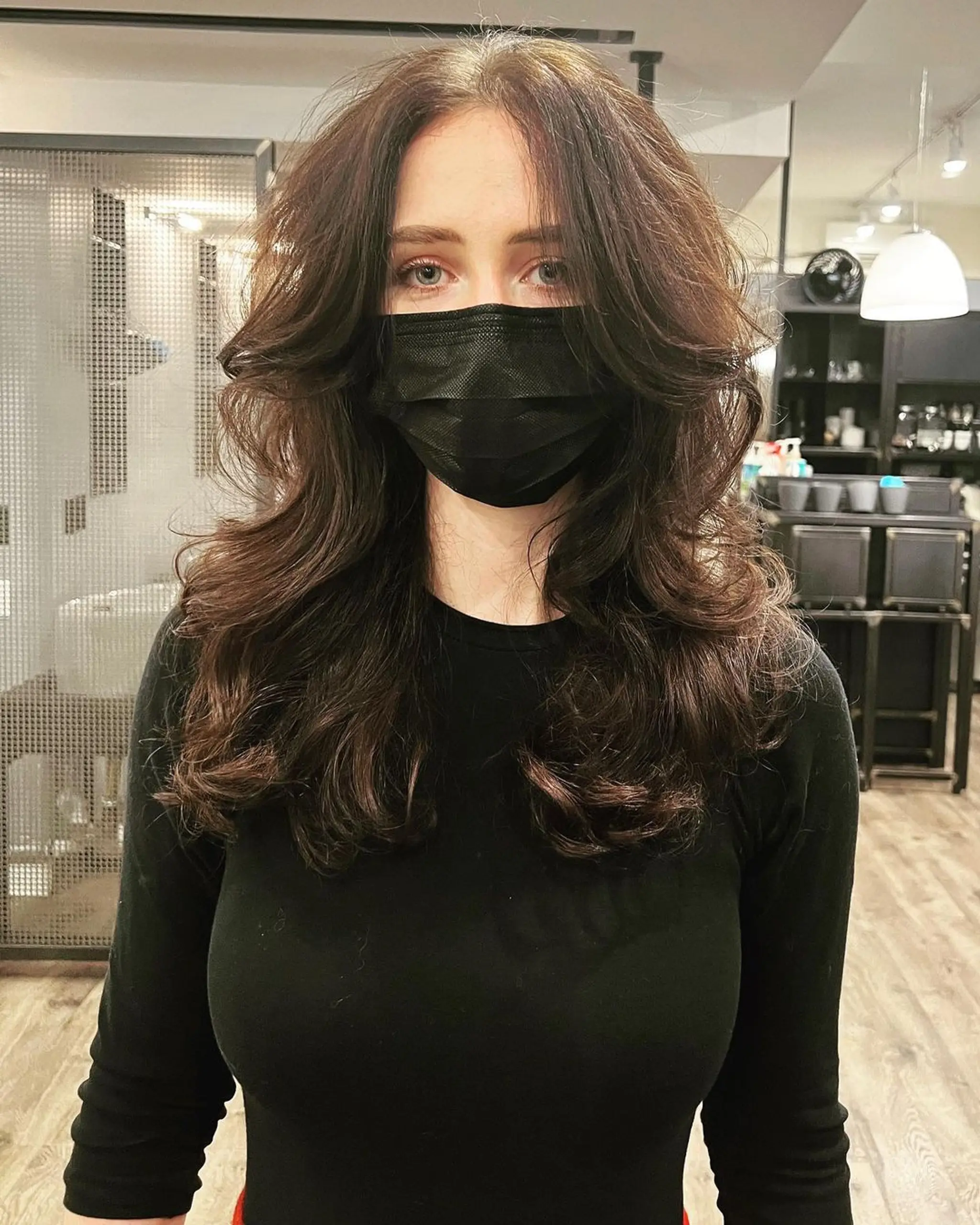 Flowing, voluminous layered hairstyle on long, dark brown wavy hair with face-framing layers and natural waves.