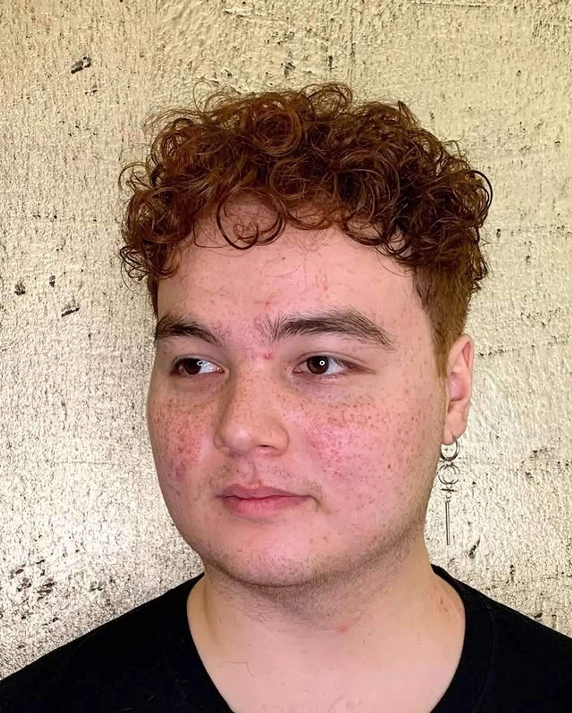 A short, textured haircut with a fade on the sides and a curly top. 1