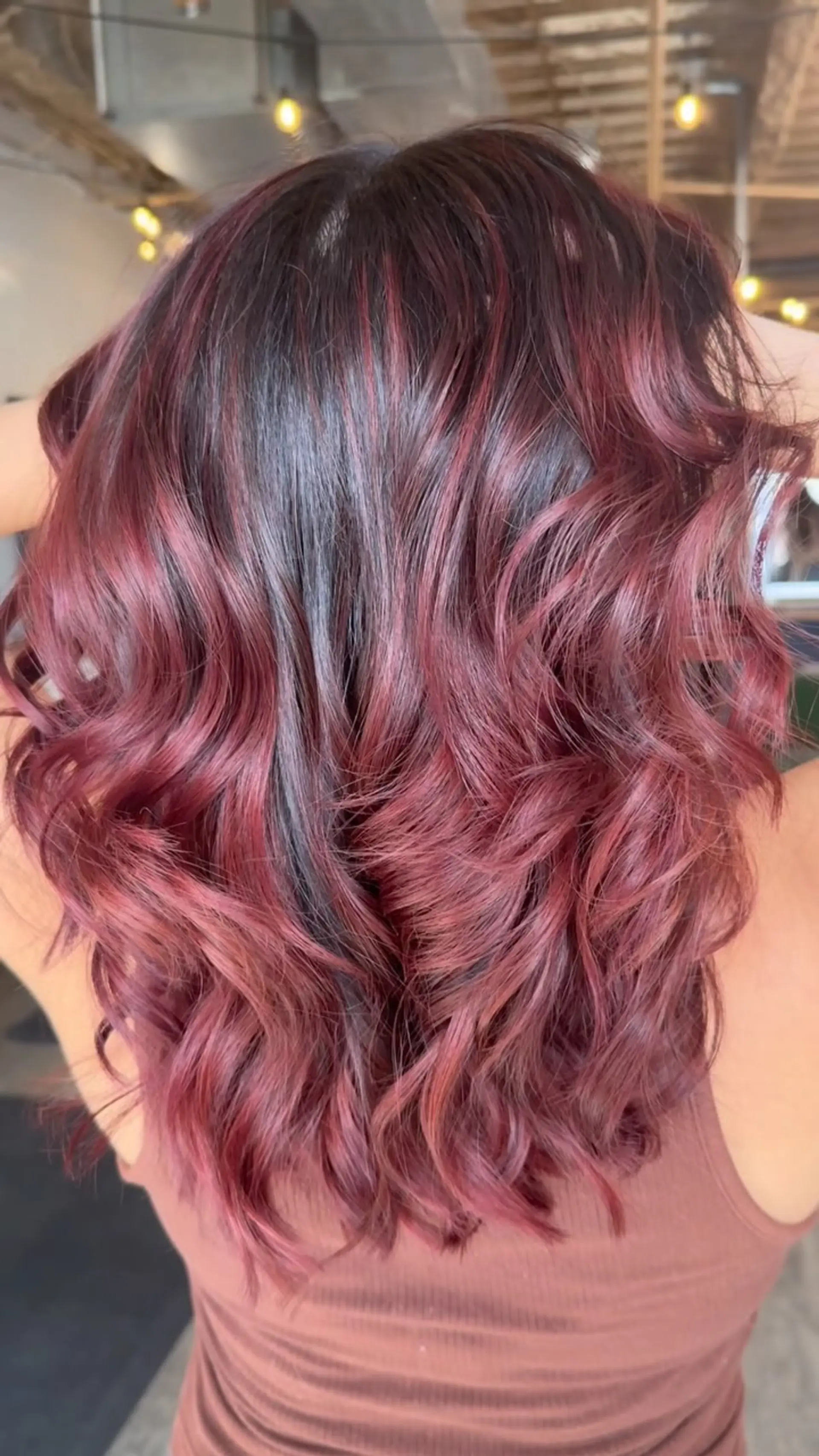 Medium-length dark brown hair featuring rich mahogany and red balayage highlights styled in soft curls. 1