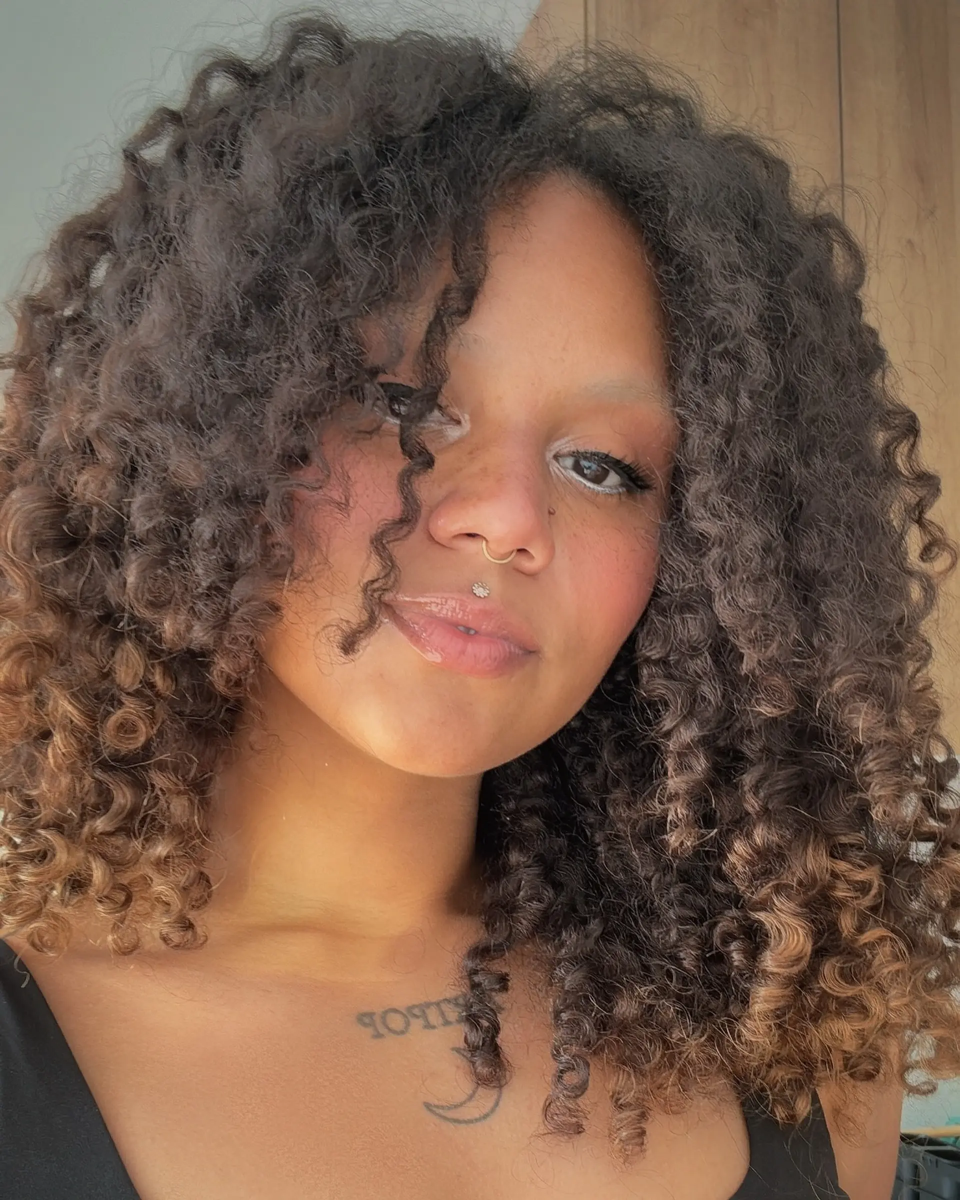 Medium-length defined tight curls with natural volume and subtle warm caramel ends. 1