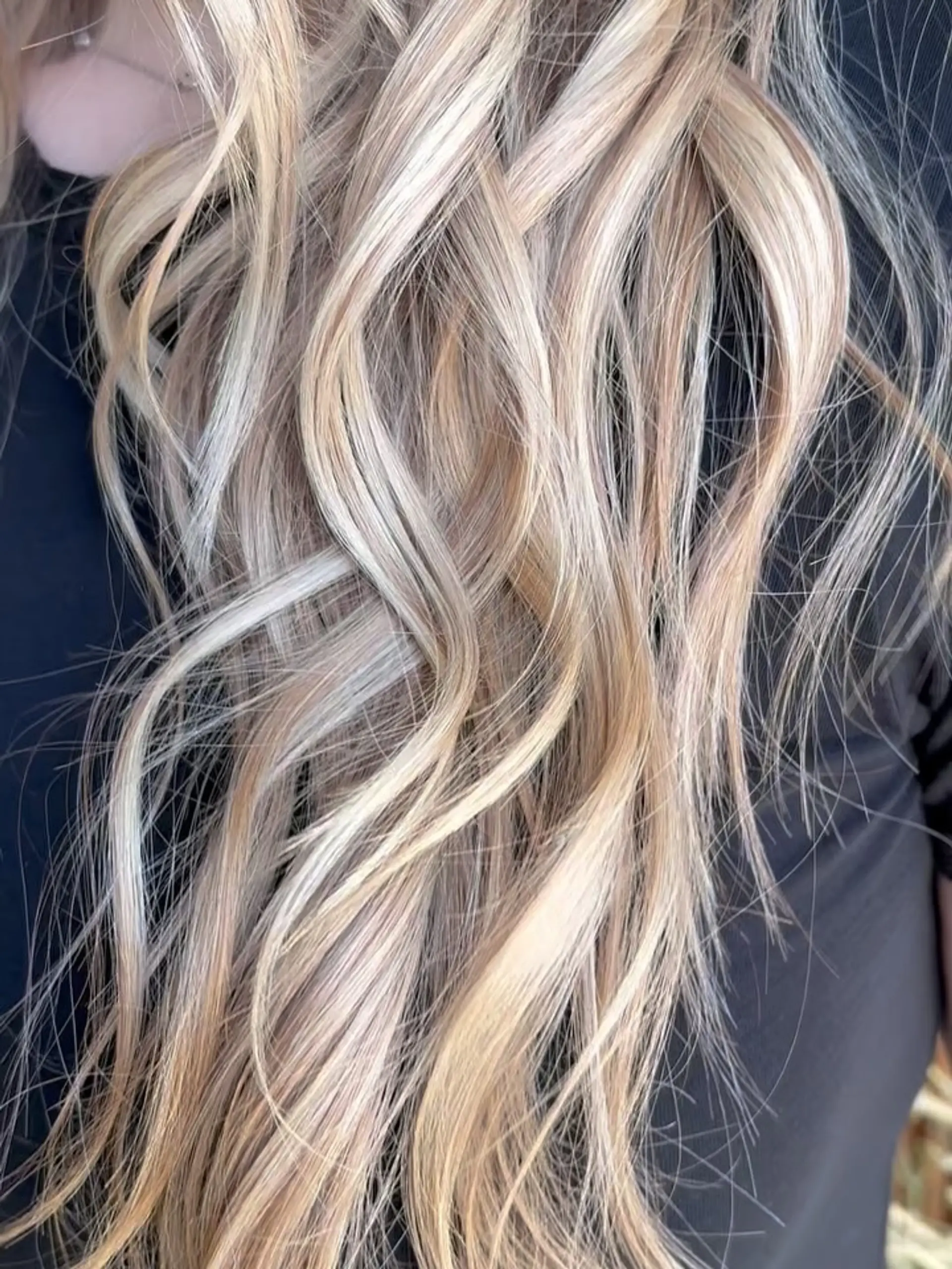 Long hair featuring dimensional multi-toned blonde highlights styled in loose, textured waves. 1