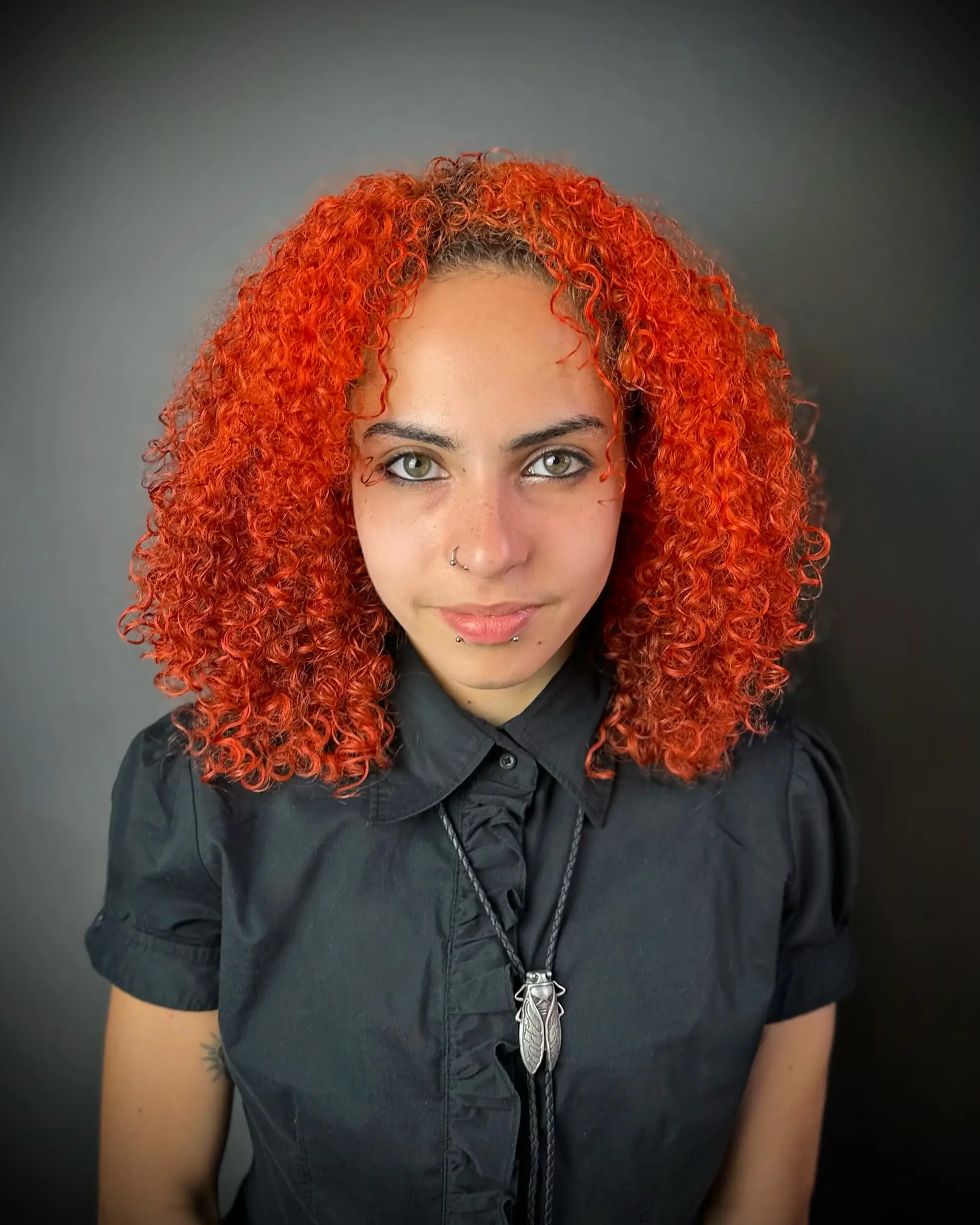 Shoulder-length tight curls cut with rounded shaping, styled in a bold, vibrant neon orange shade. 1