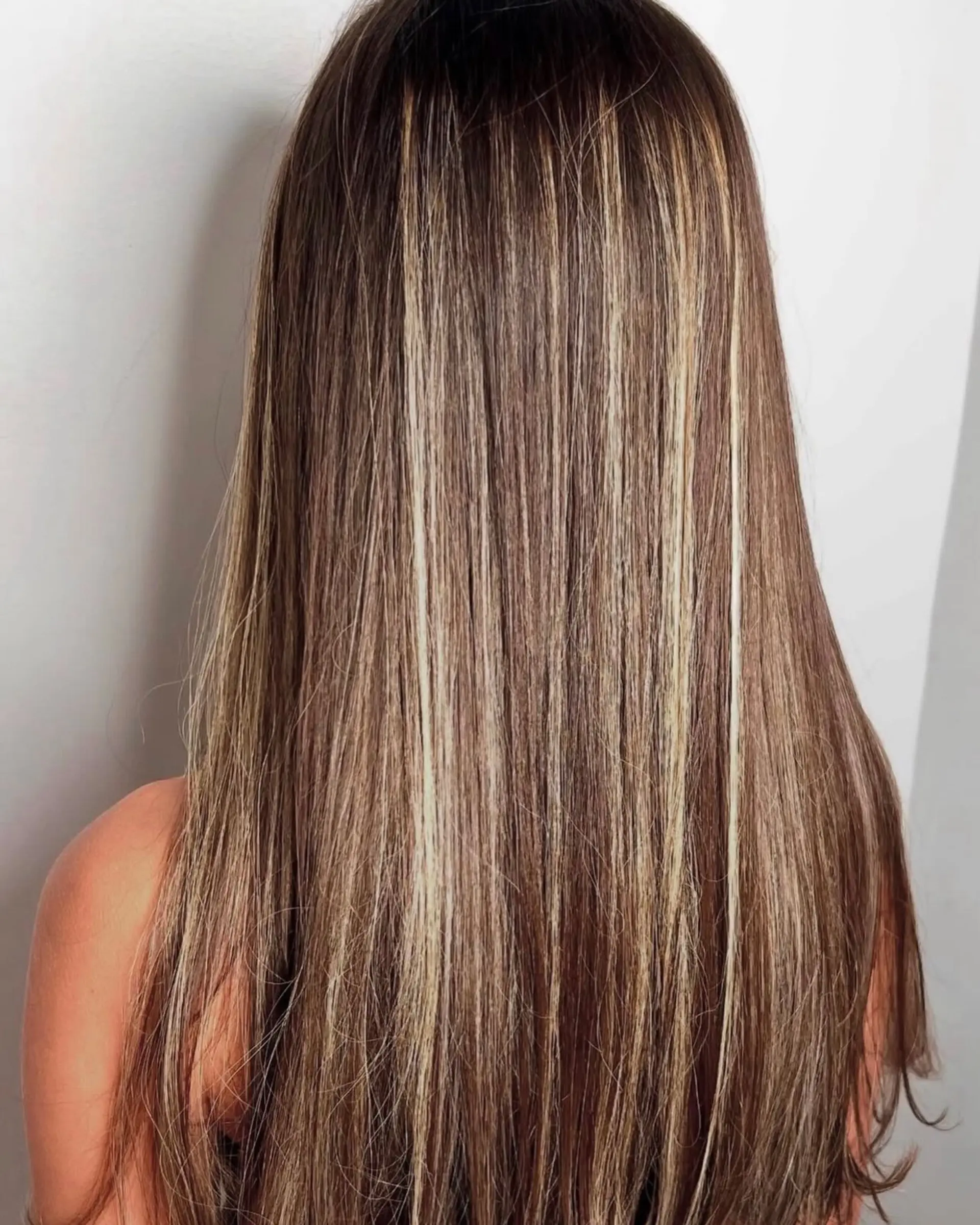 Long, straight brunette hair enhanced with fine blonde highlights throughout for dimension. 1