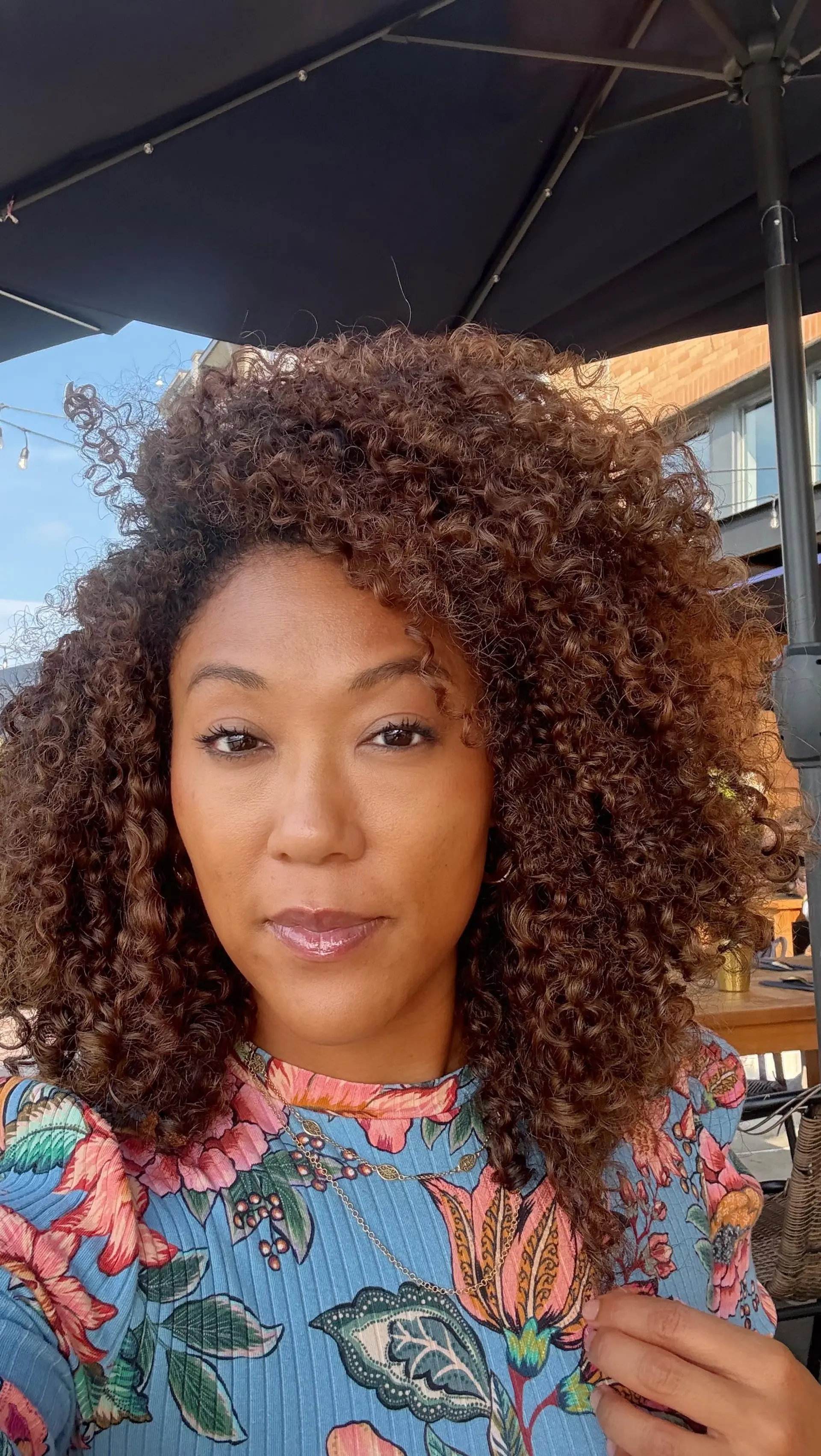 Full, voluminous medium-length style with tightly defined, healthy curls and warm brunette tones. 1