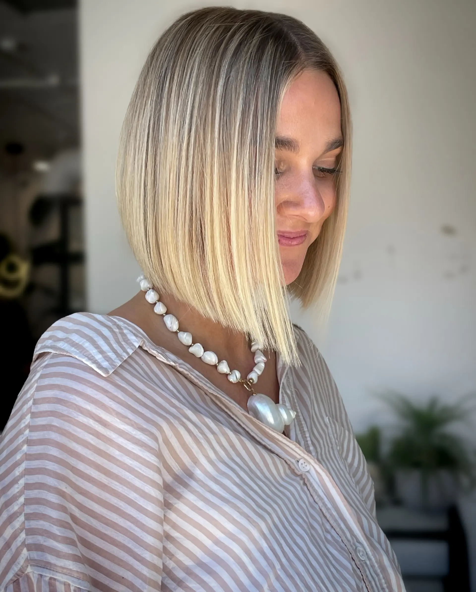 A sleek, precision-cut blunt bob that gently angles forward with smooth, straight styling and dimensional blonde highlights. 1