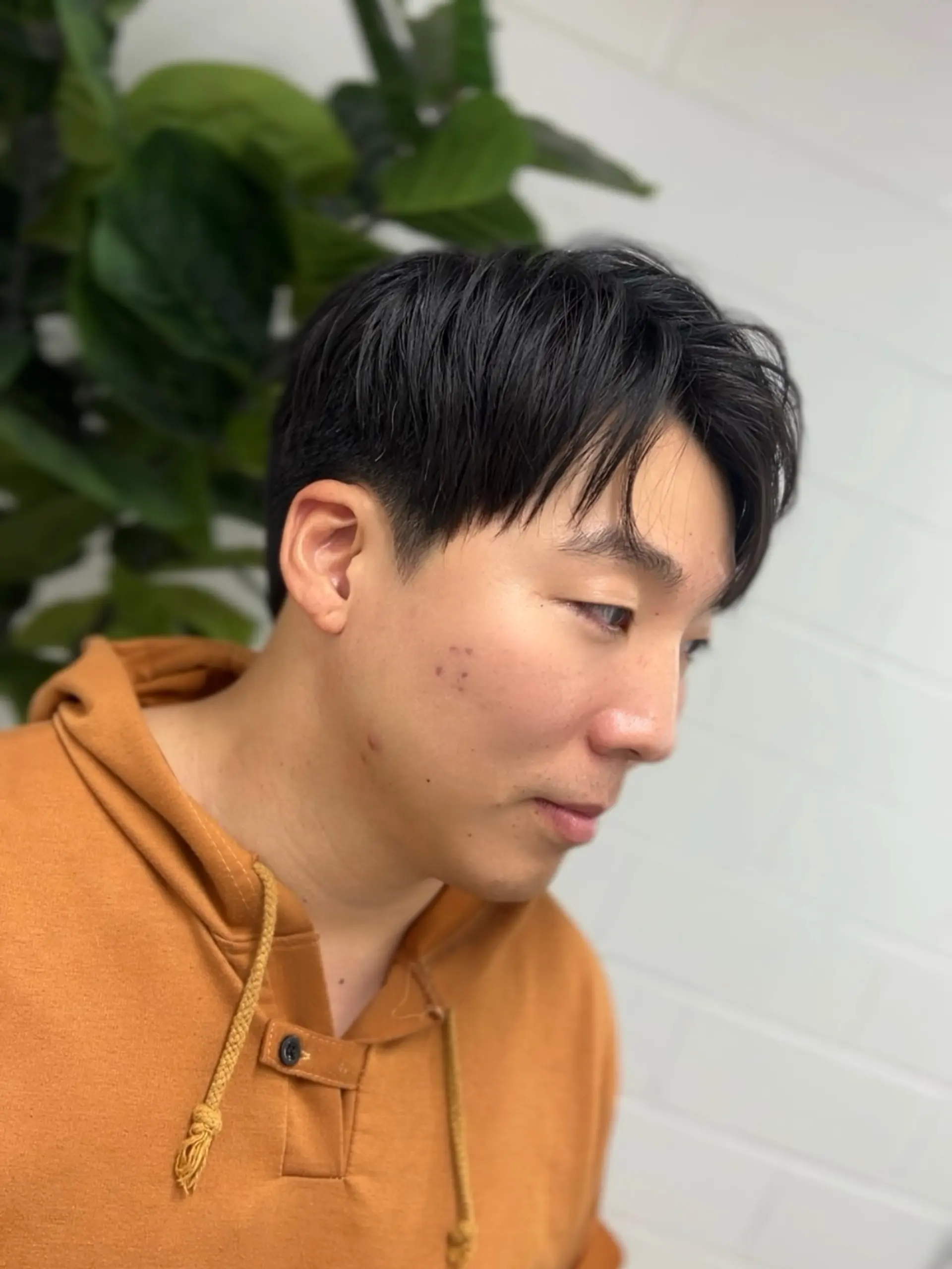 A modern soft two-block haircut featuring neat, tapered sides with longer, textured layers and a wispy parted fringe on top. 1