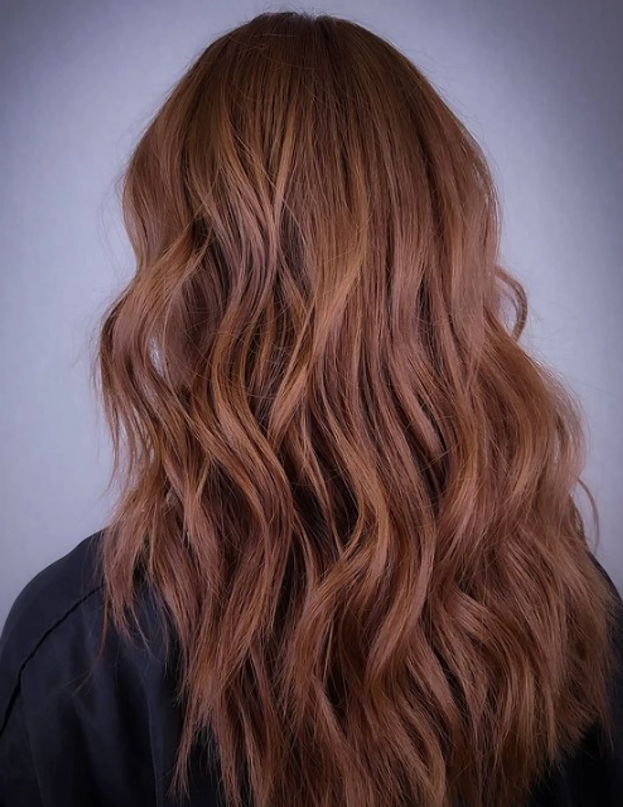 Long, wavy, auburn hair with natural, loose beach waves and layered cut, adding dimension and volume.
