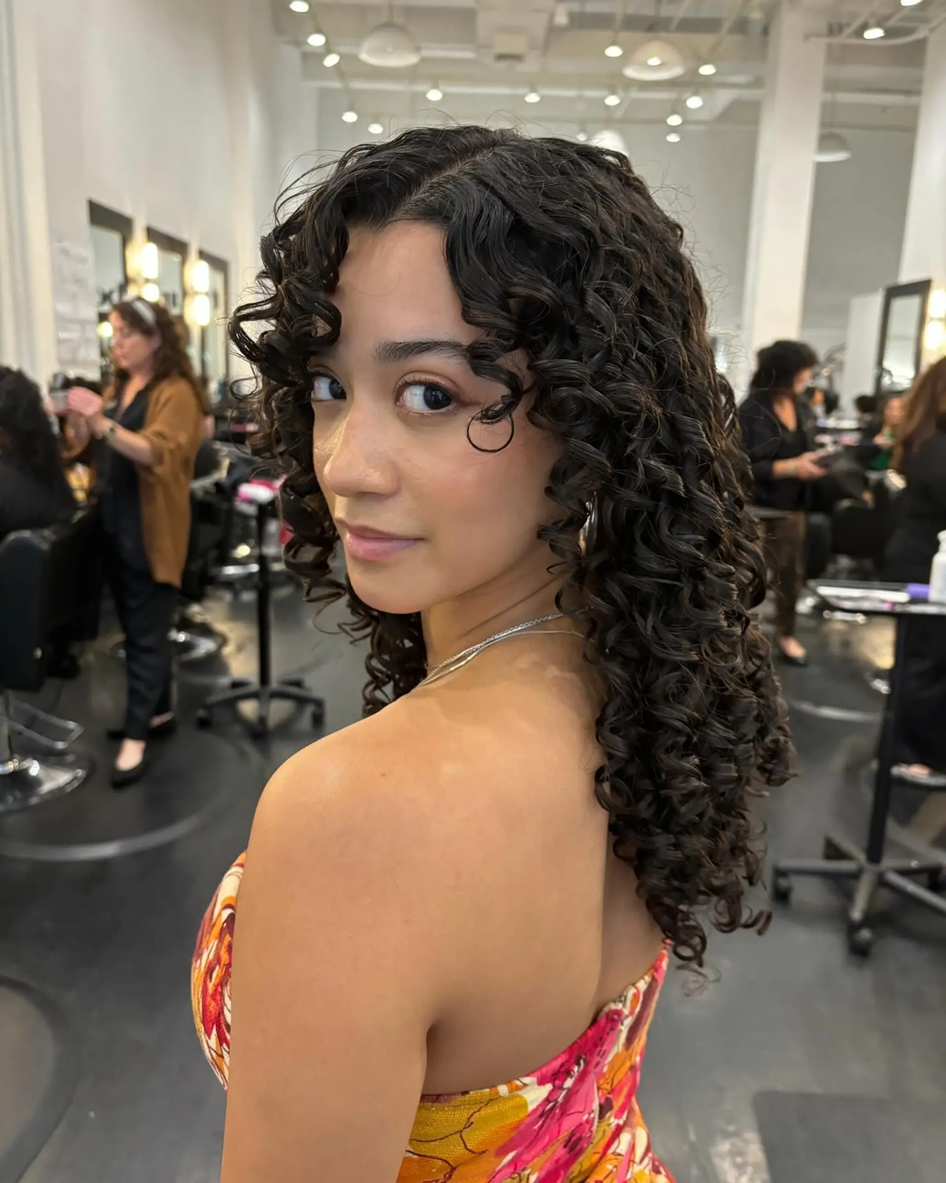 Well-defined, glossy brunette ringlet curls with soft curly bangs framing the face. 1