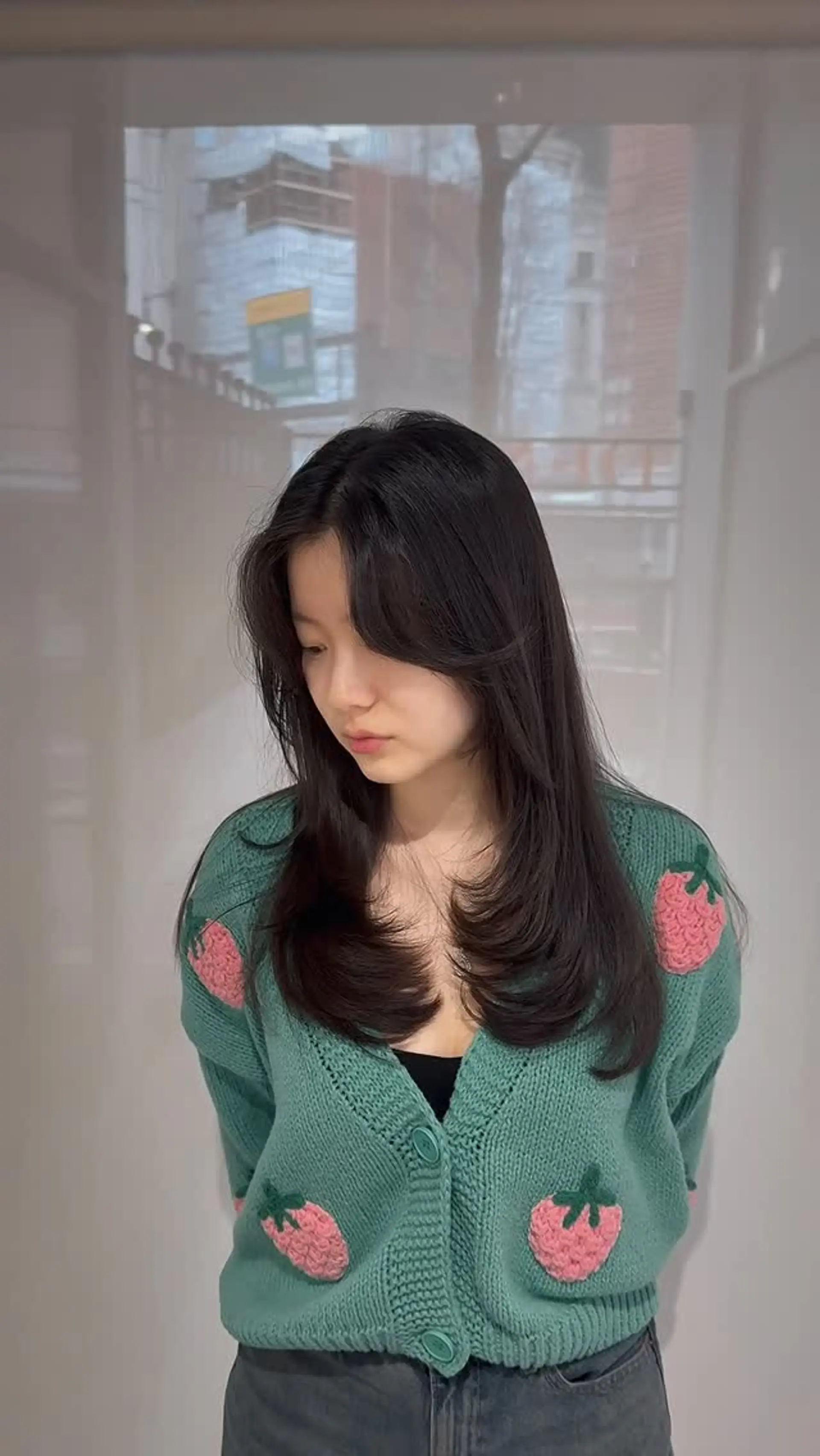 Chest-length dark layered cut styled with soft inward C-curls and face-framing curtain bangs. 1