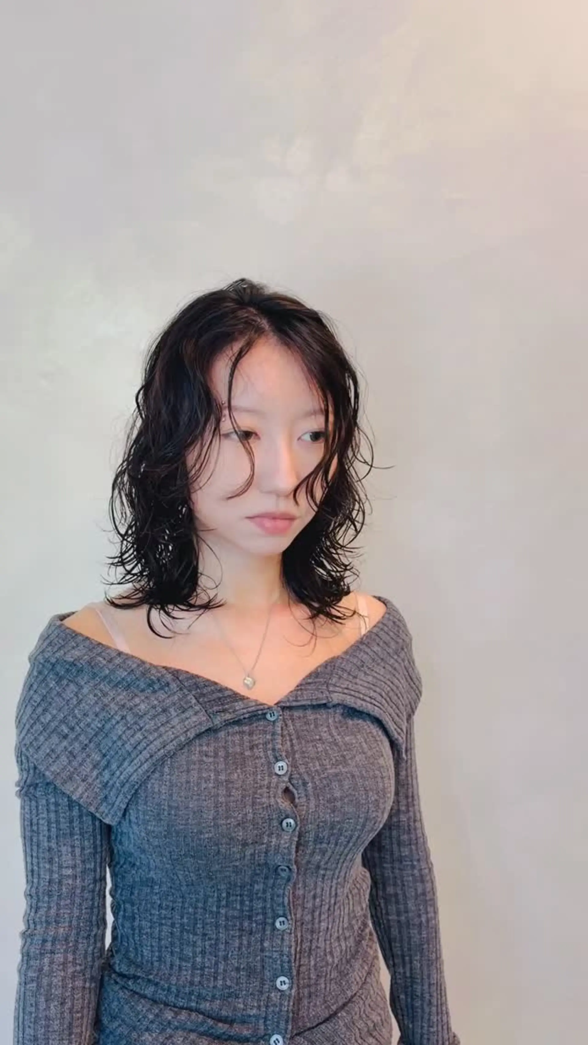 Shoulder-length dark hair styled with piecey, wet-look waves and face-framing curly tendrils. 1
