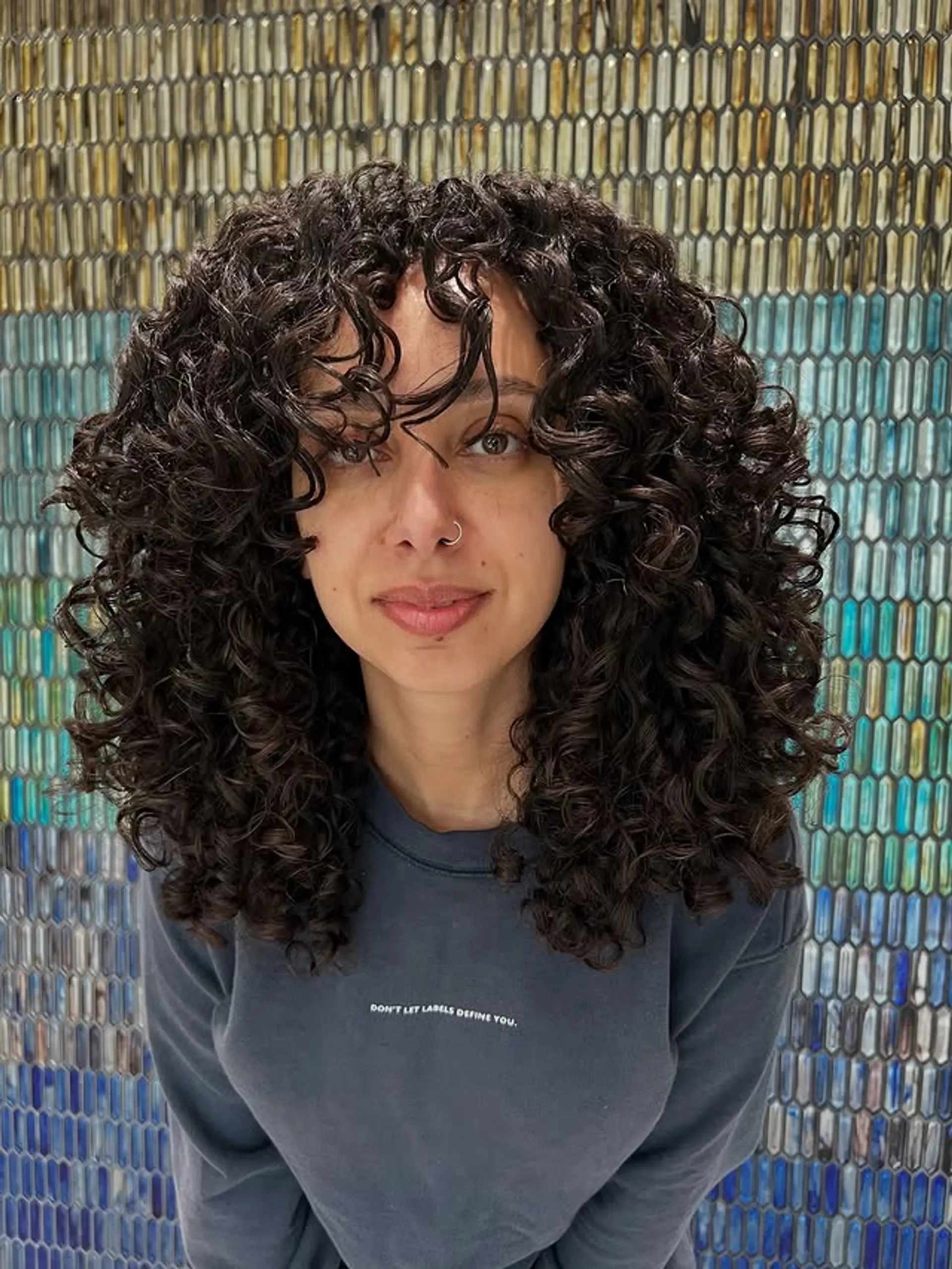A chic medium-length curly cut with layers and face-framing curly bangs. This style enhances natural curl definition and volume. 1