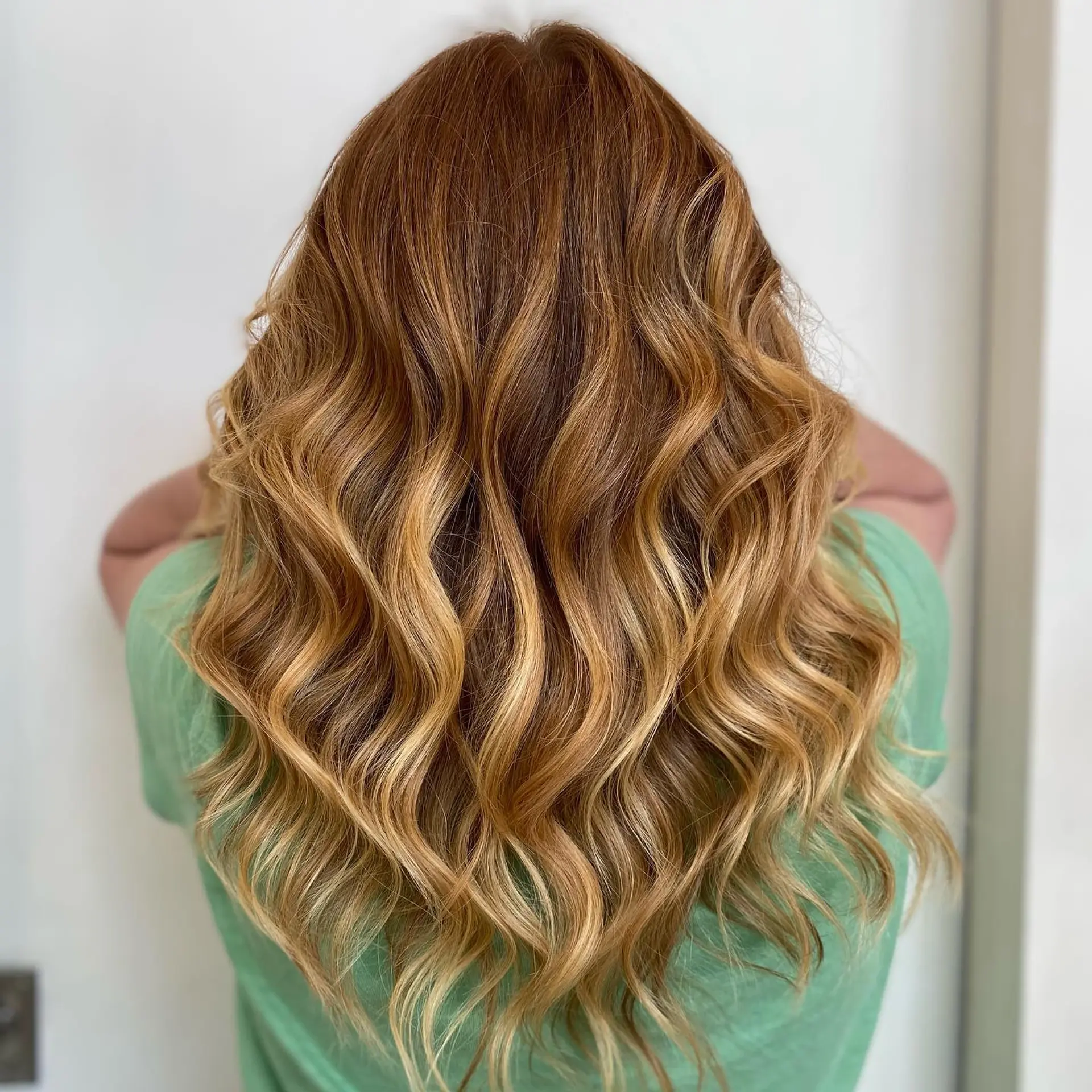 Long dimensional auburn hair with warm golden and honey blonde balayage styled in soft waves. 1