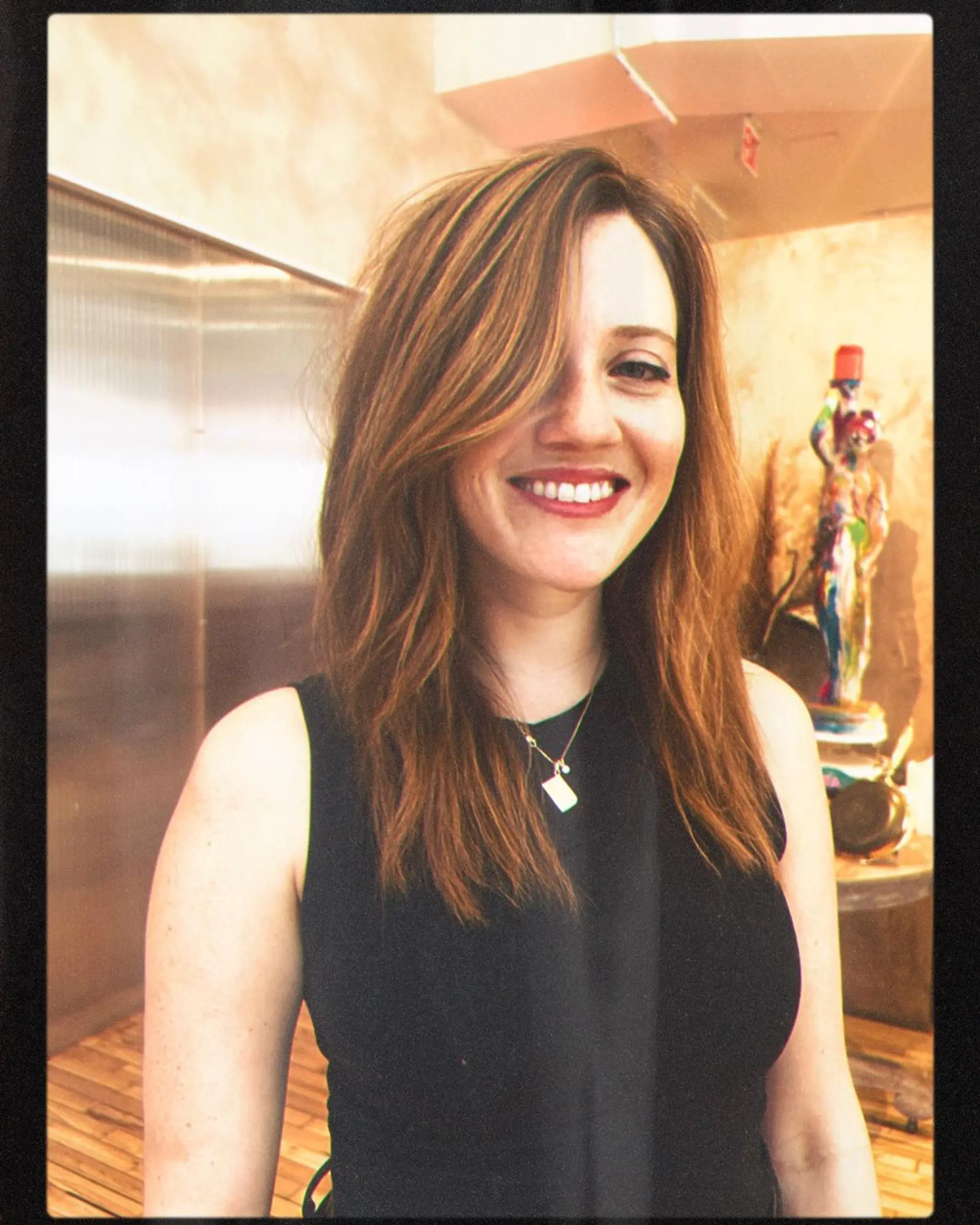 Medium-length, naturally wavy, layered cut with side-swept bangs and chestnut brown hair with golden highlights.