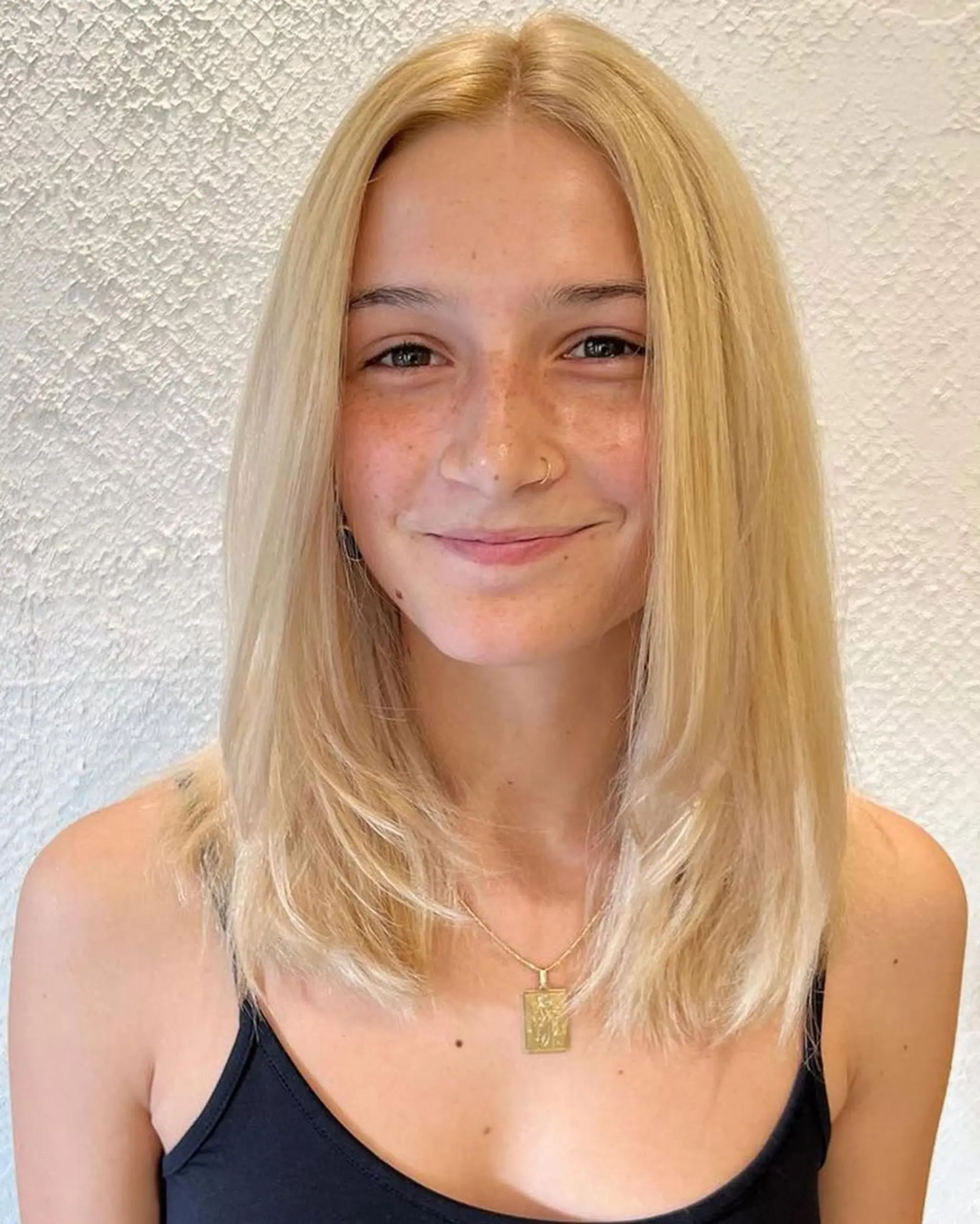 Medium length, straight blonde hair with soft layers and a center part.