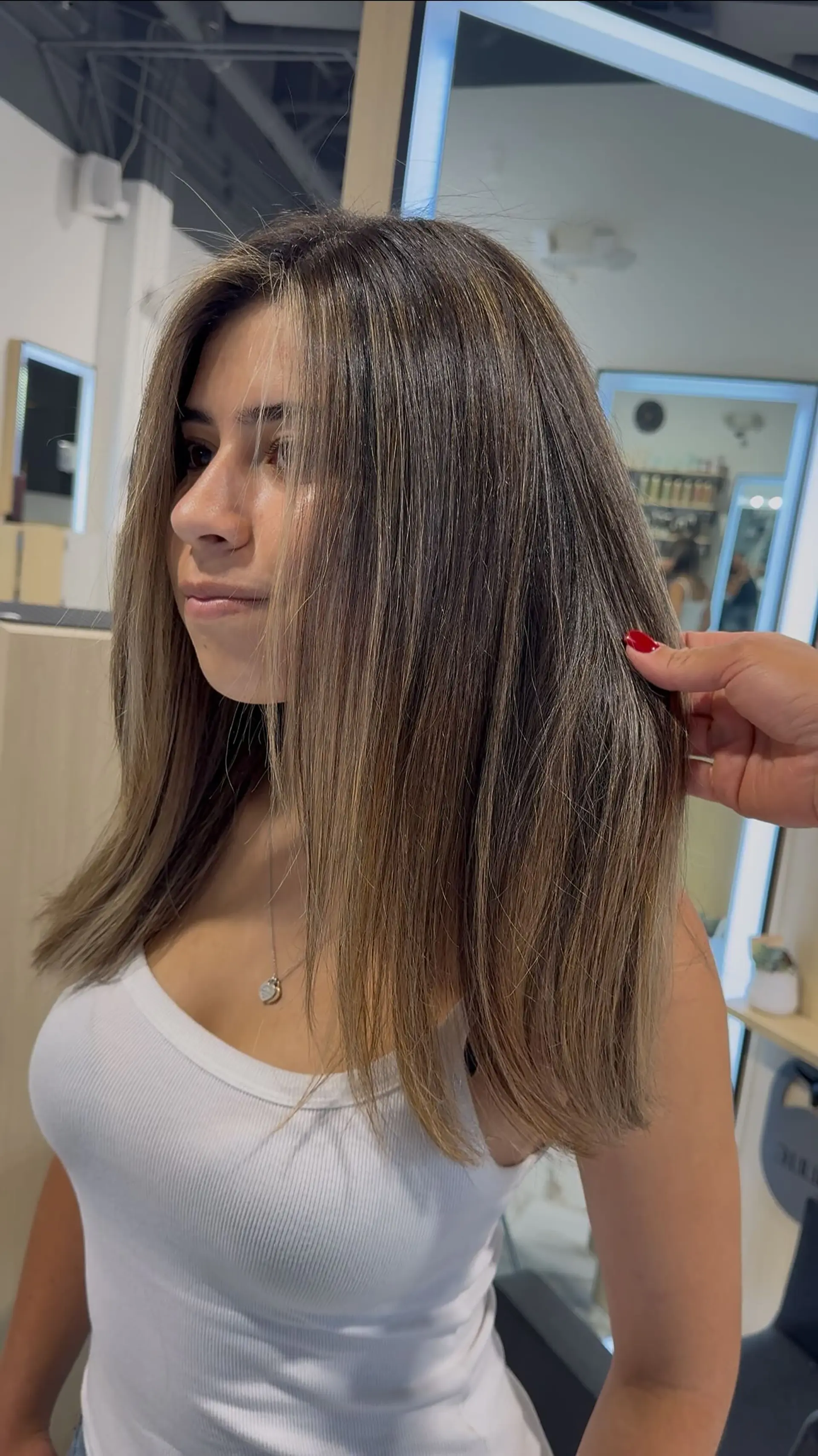 Medium-length straight hair styled with seamless dimensional bronde highlights and soft face-framing layers. 1