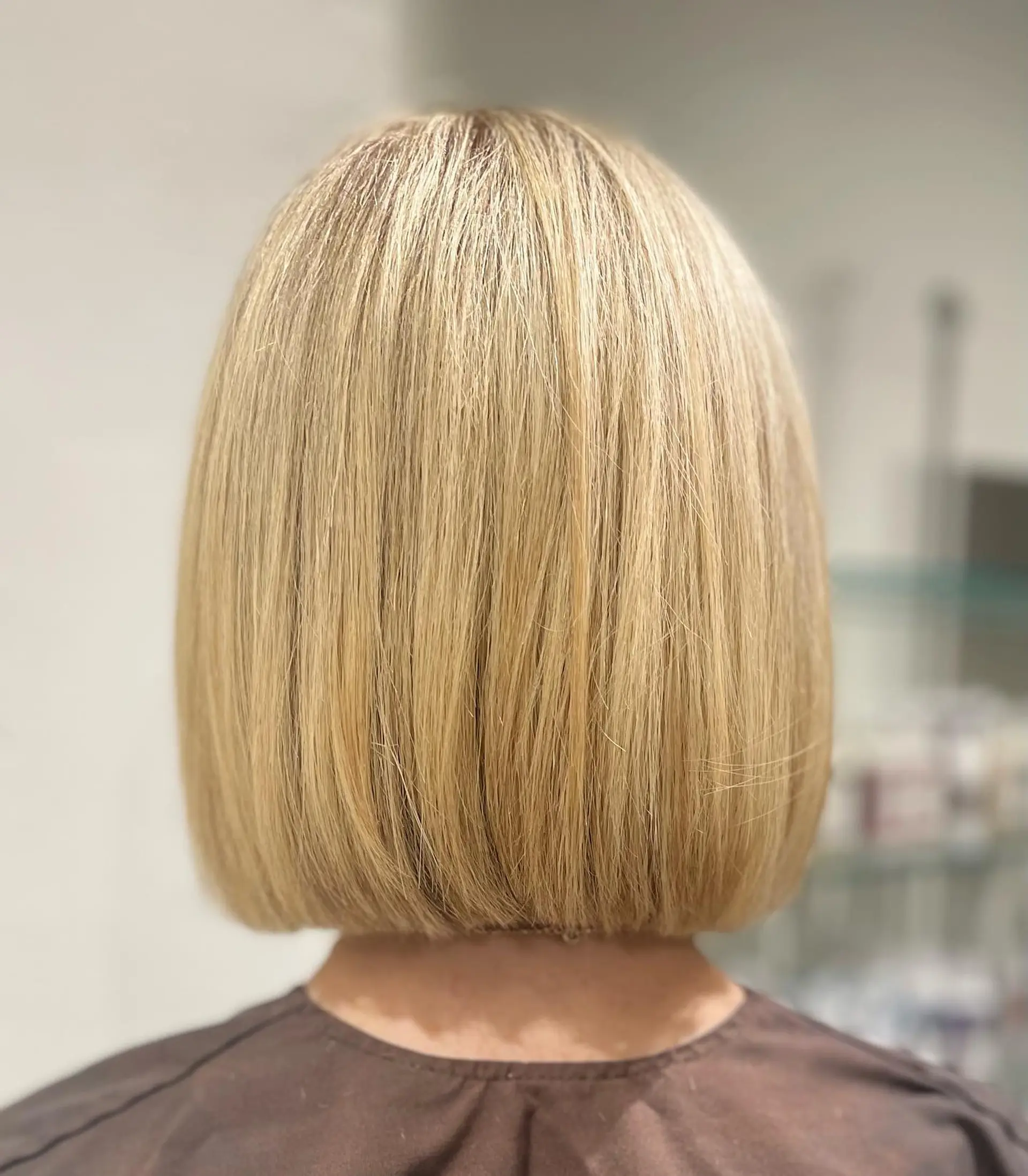A sleek, classic one-length bob cut cleanly at the nape of the neck with seamless blonde highlights. 1