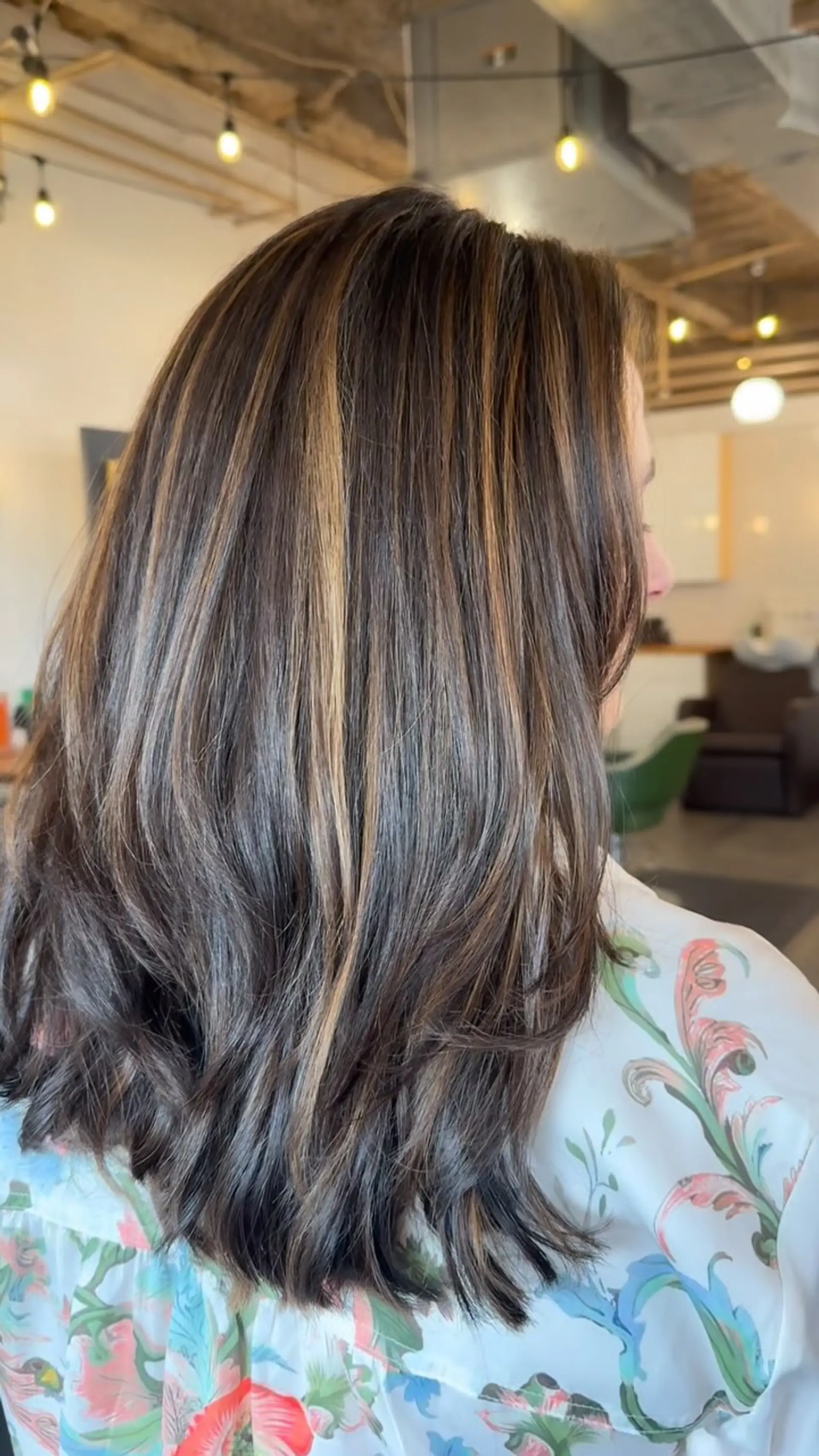 Medium-length dark brown hair featuring warm caramel highlights and soft textured layers. 1