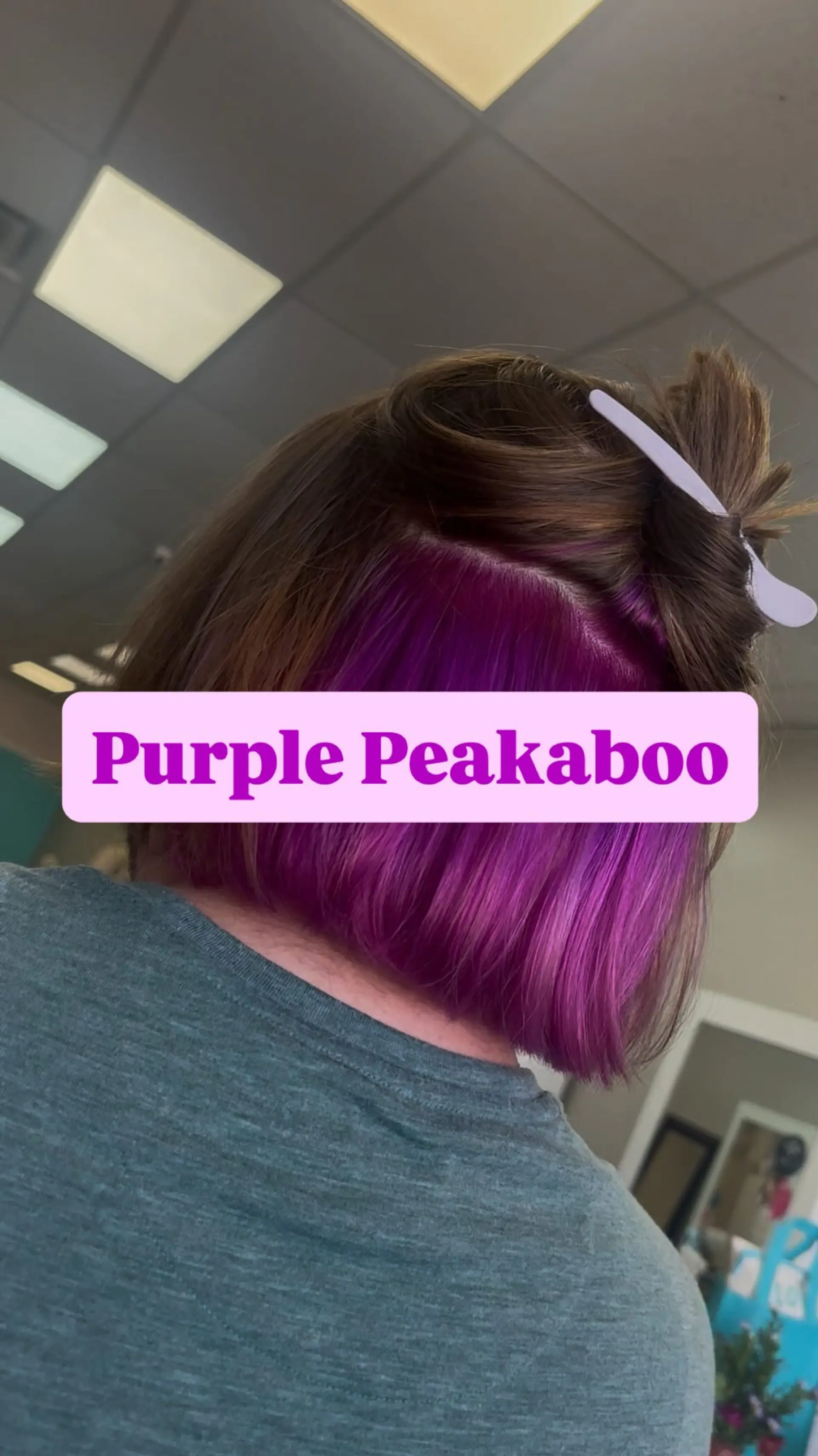 A blunt short bob featuring a striking vivid purple peekaboo underlayer beneath natural brunette hair. 1