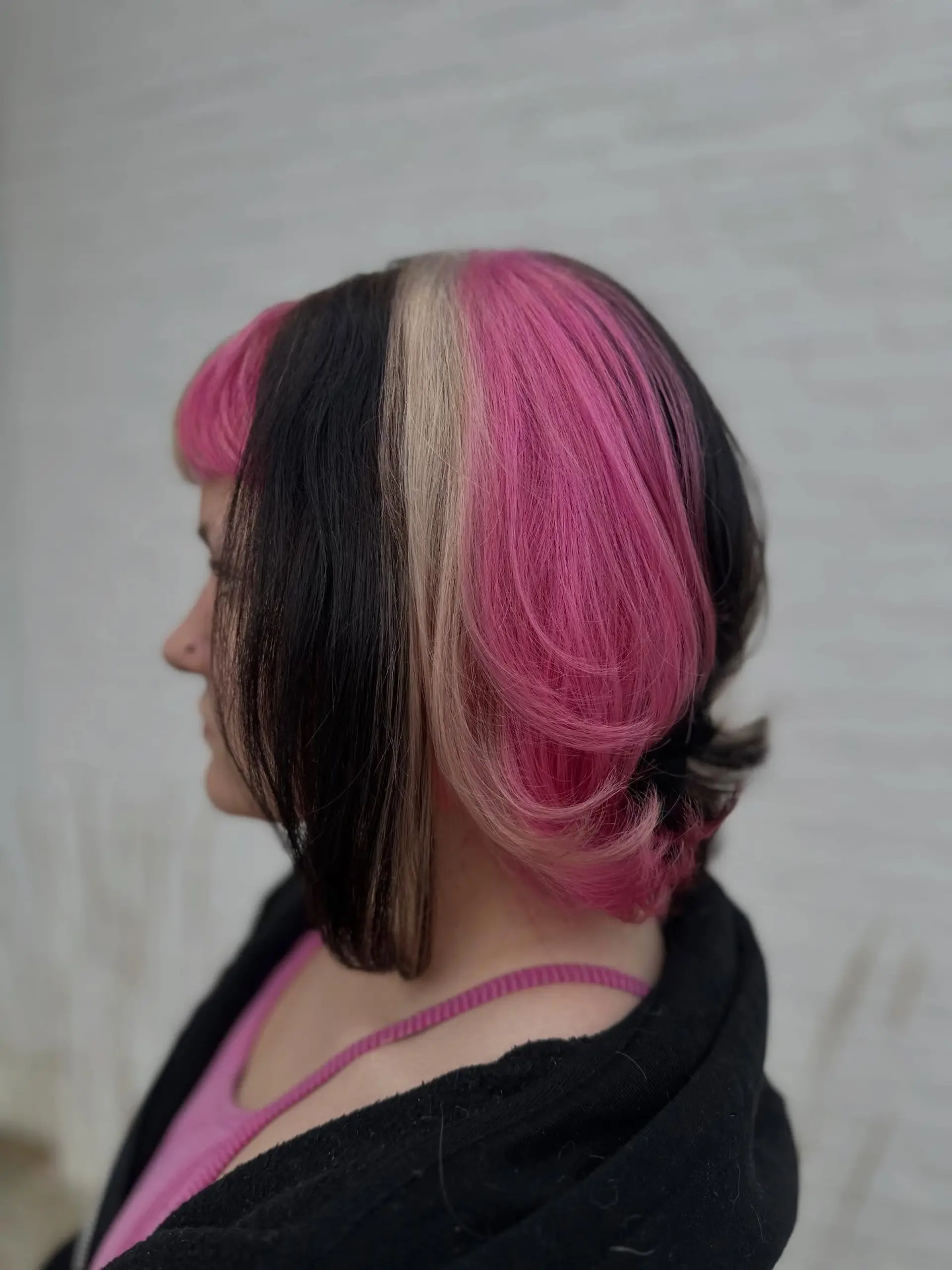 A sleek short bob featuring bold Neapolitan-inspired color blocking in dark brown, blonde, and vivid pink, complemented by short bangs. 1