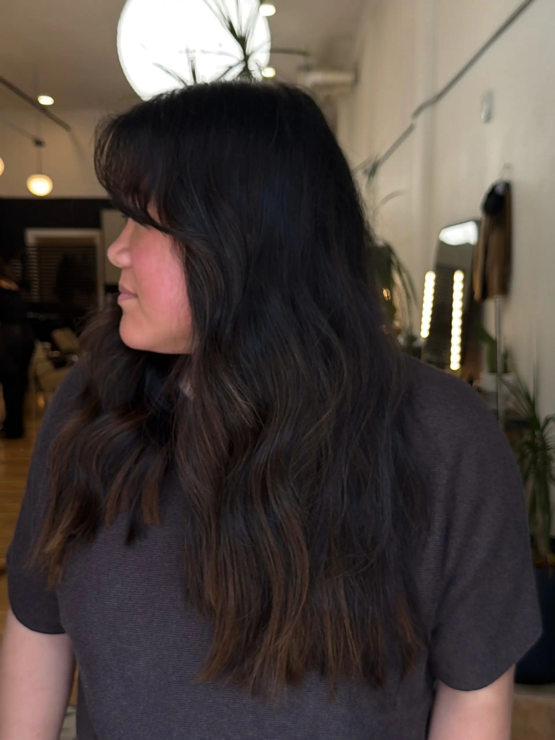 Long espresso brunette hair styled in loose effortless waves featuring a full front fringe. 1
