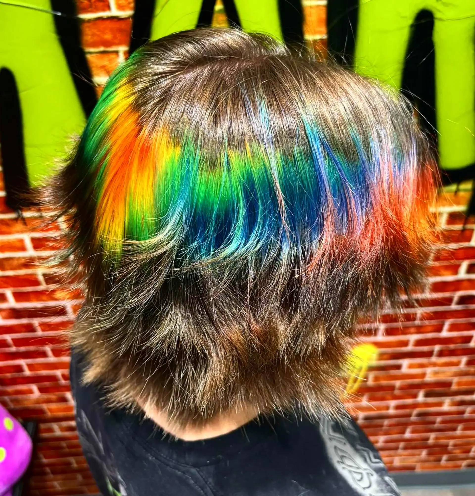 A textured short brunette haircut featuring a vibrant horizontal rainbow halo band running across the mid-lengths. 1