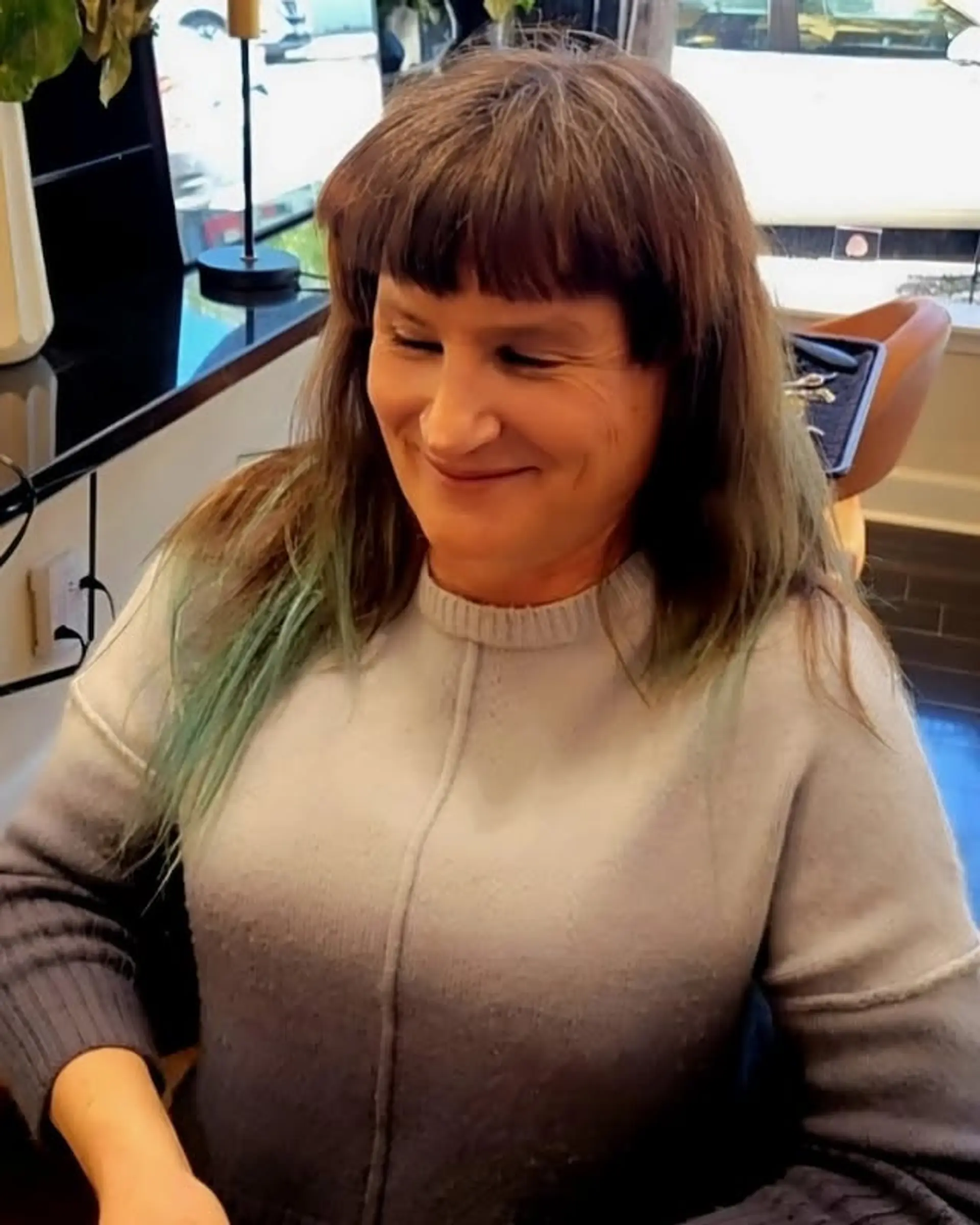 A medium-length, straight hairstyle characterized by a bold, blunt, and slightly choppy fringe, complemented by striking teal and green dip-dyed ends. 1