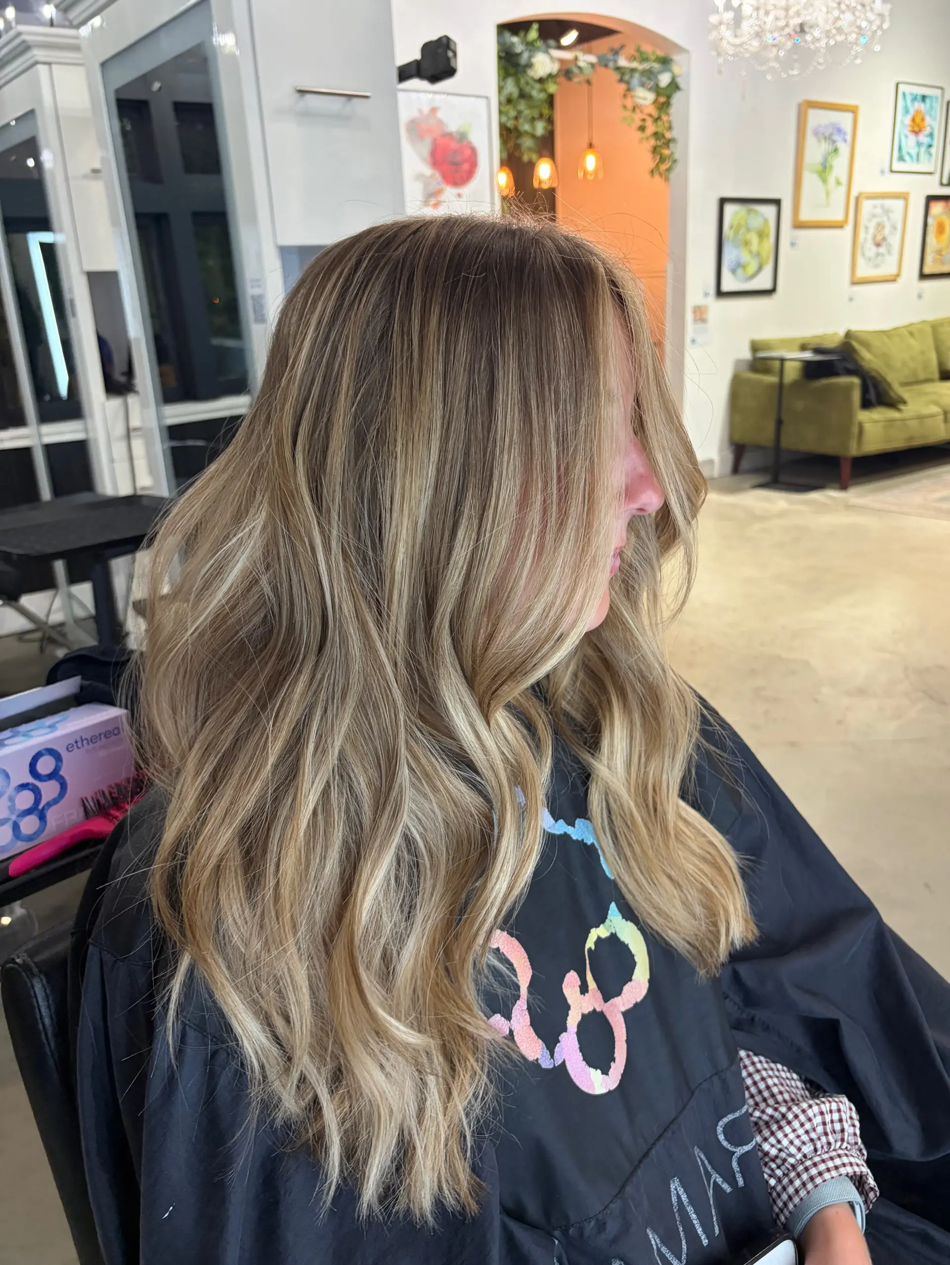 Long dimensional blonde hair featuring blended highlights and lowlights, styled in loose soft waves. 1