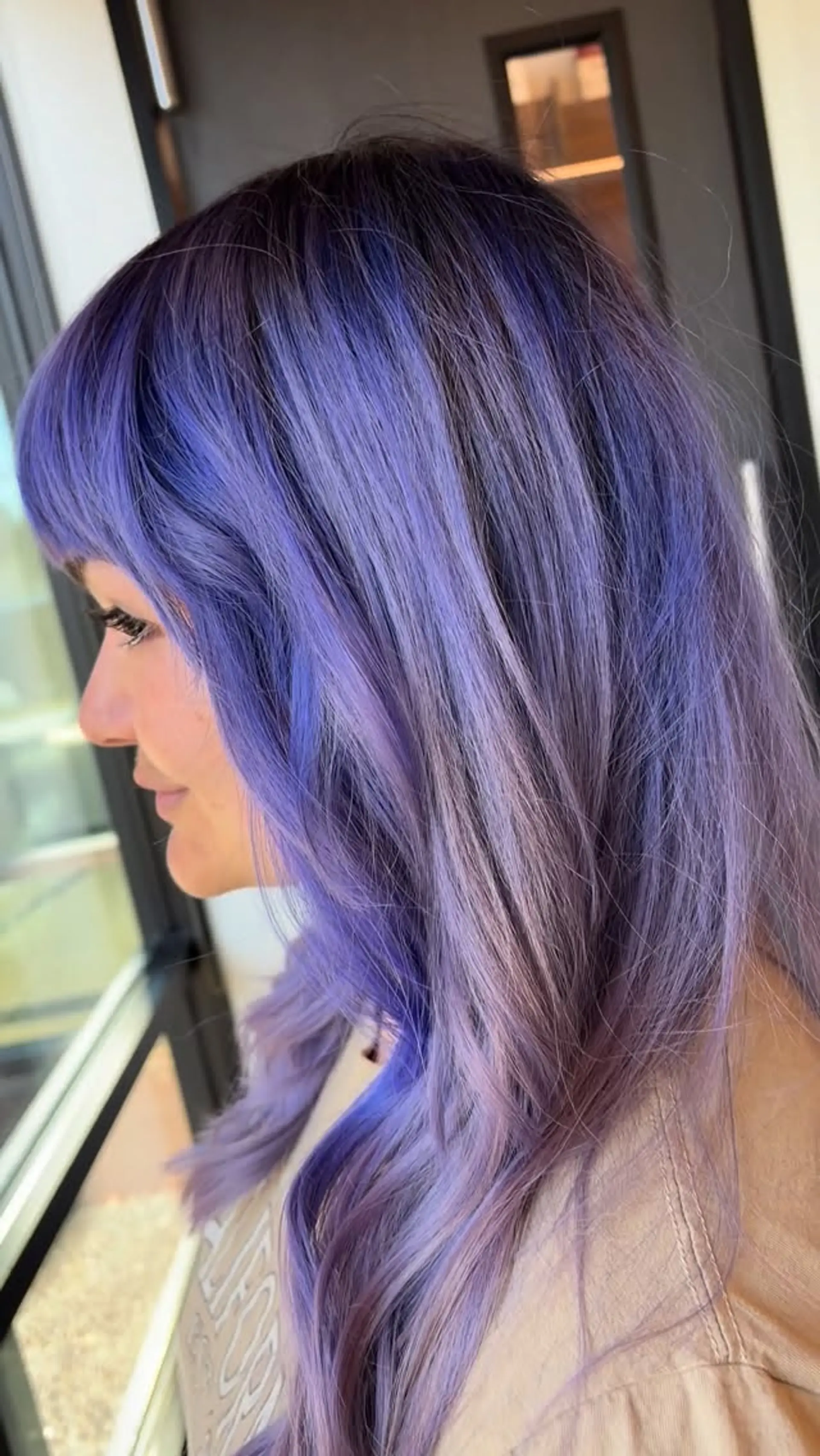 A vibrant color melt featuring dark purple roots blending into soft lavender tones with face-framing bangs. 1